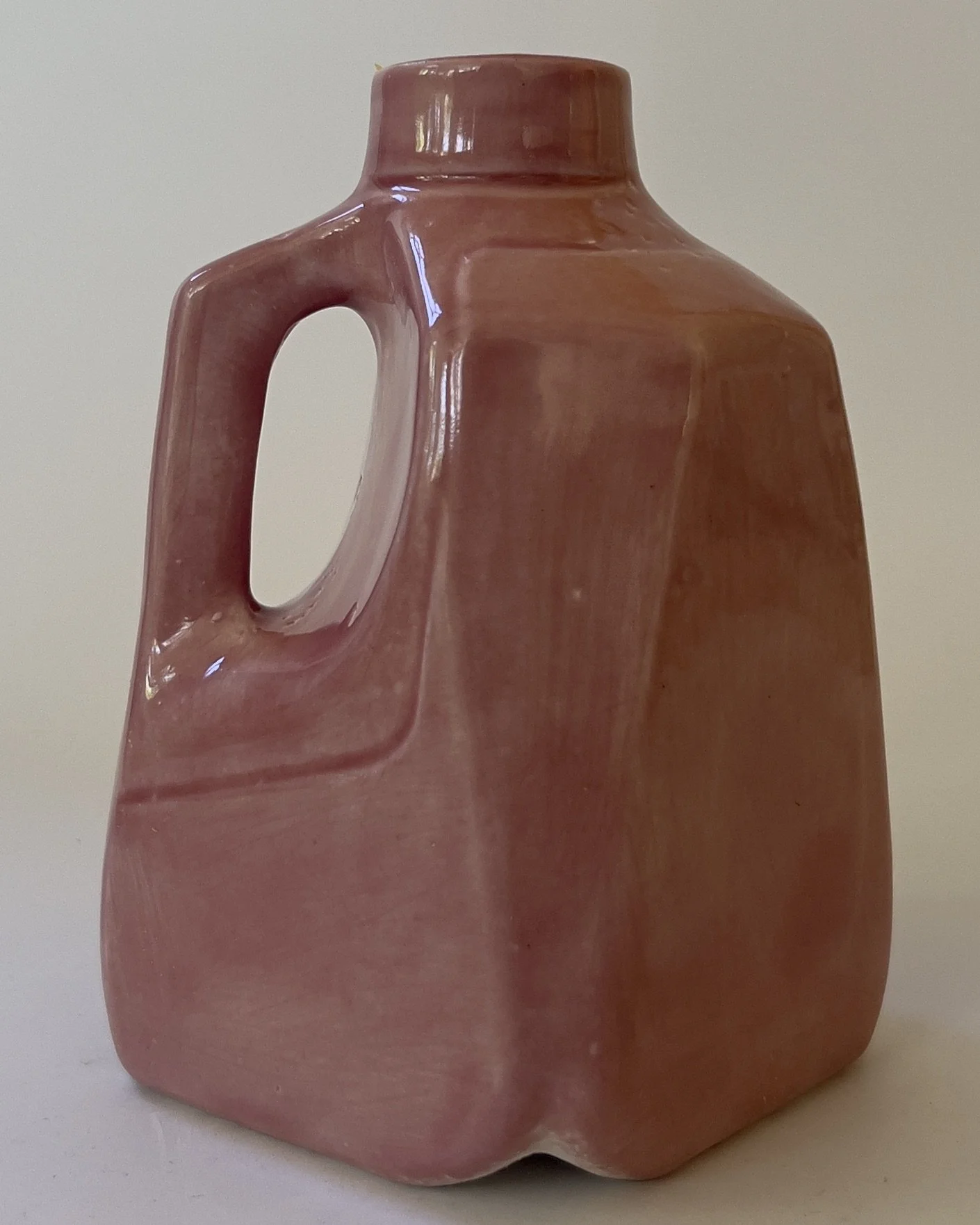 Side angle of sculptural ceramic milk jug with marbled pink glaze