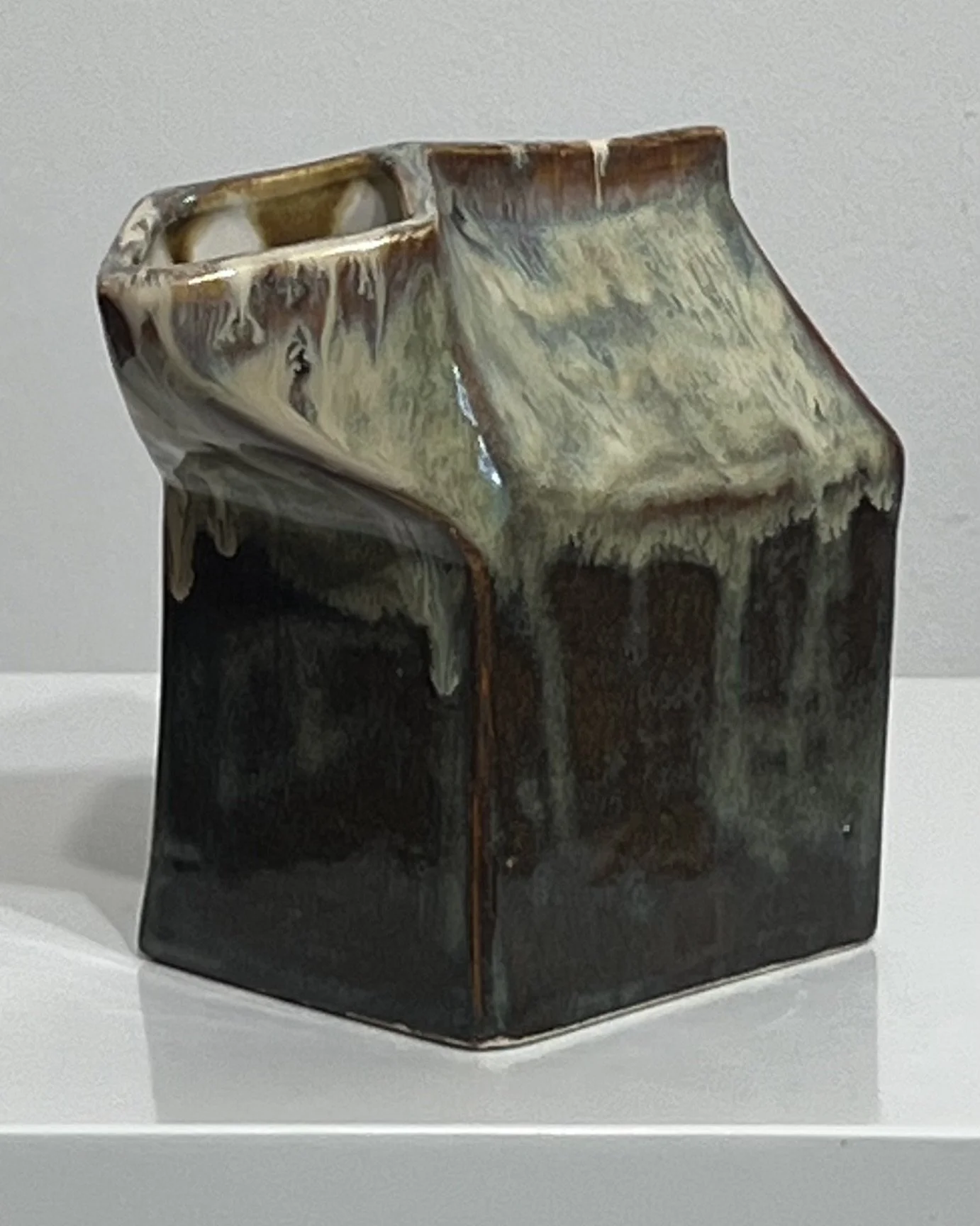 Angled view showing flowing cream glaze over dark Iron Lustre ceramic vase