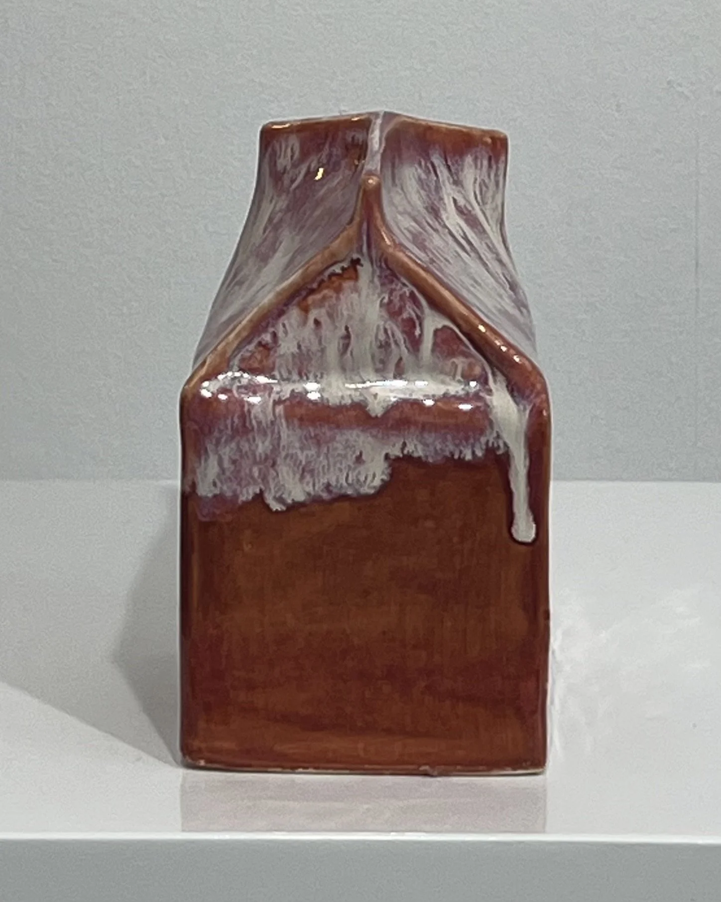 Side view of the sculptural ceramic milk carton showing the folded top and cascading Light Flux glaze.
