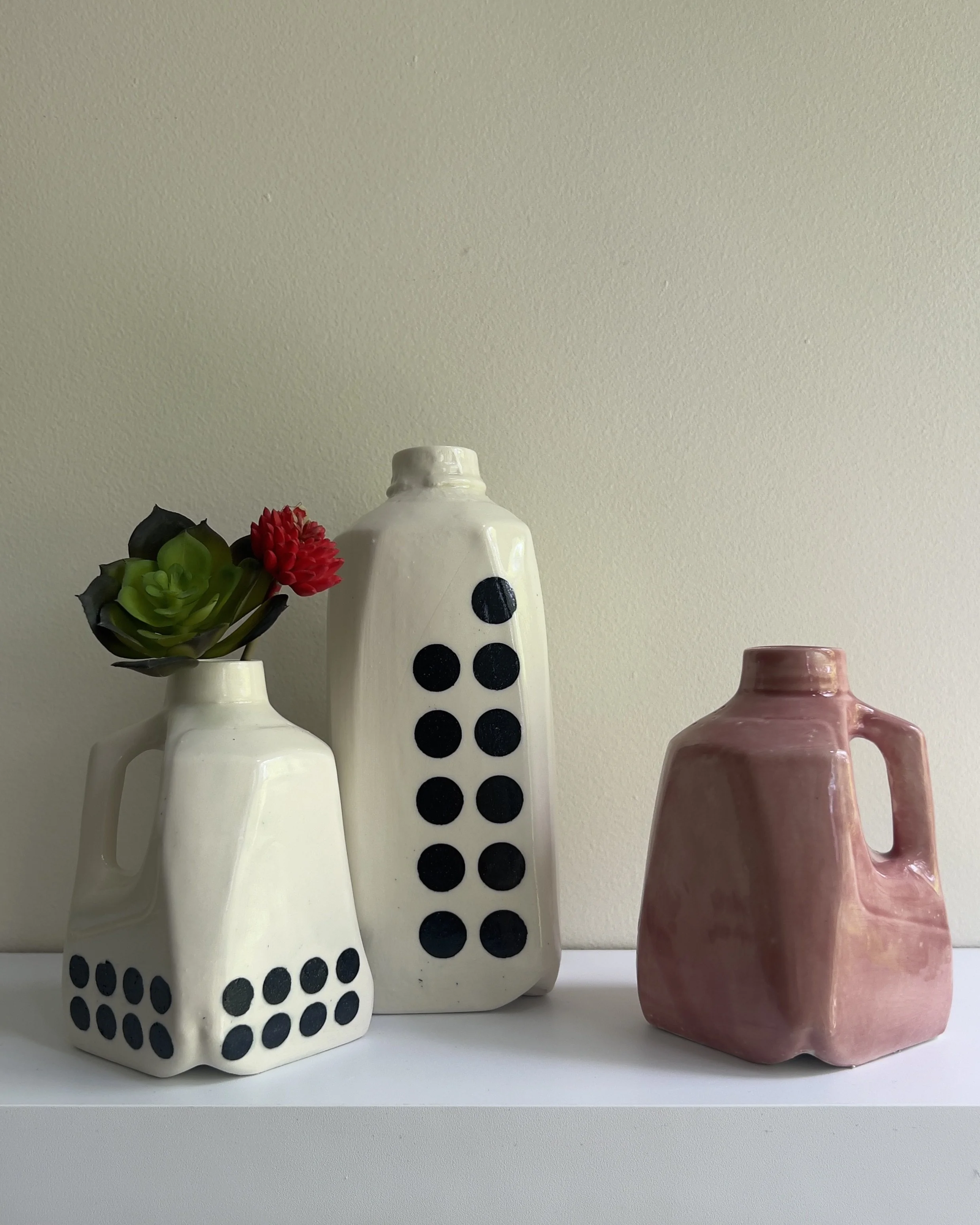 Ceramic milk jug sculpture displayed with companion vessels
