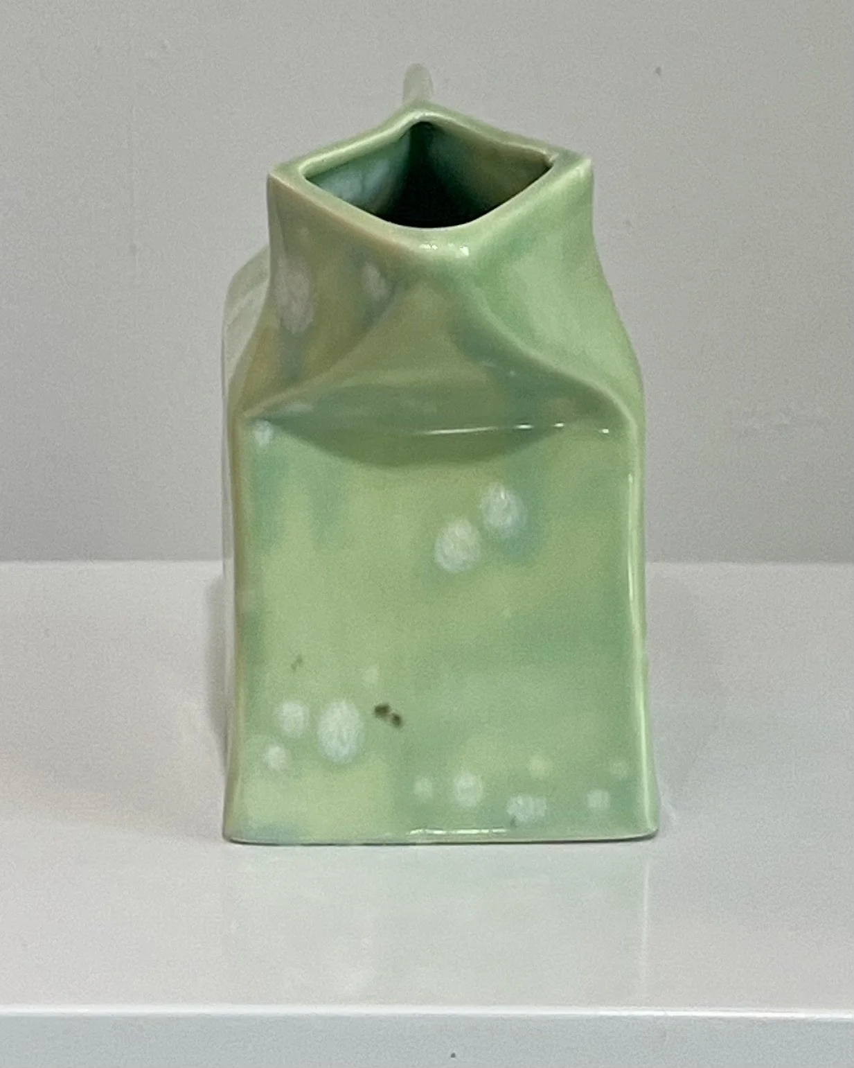 Side profile of one-of-a-kind porcelain milk carton sculpture with folded carton form.