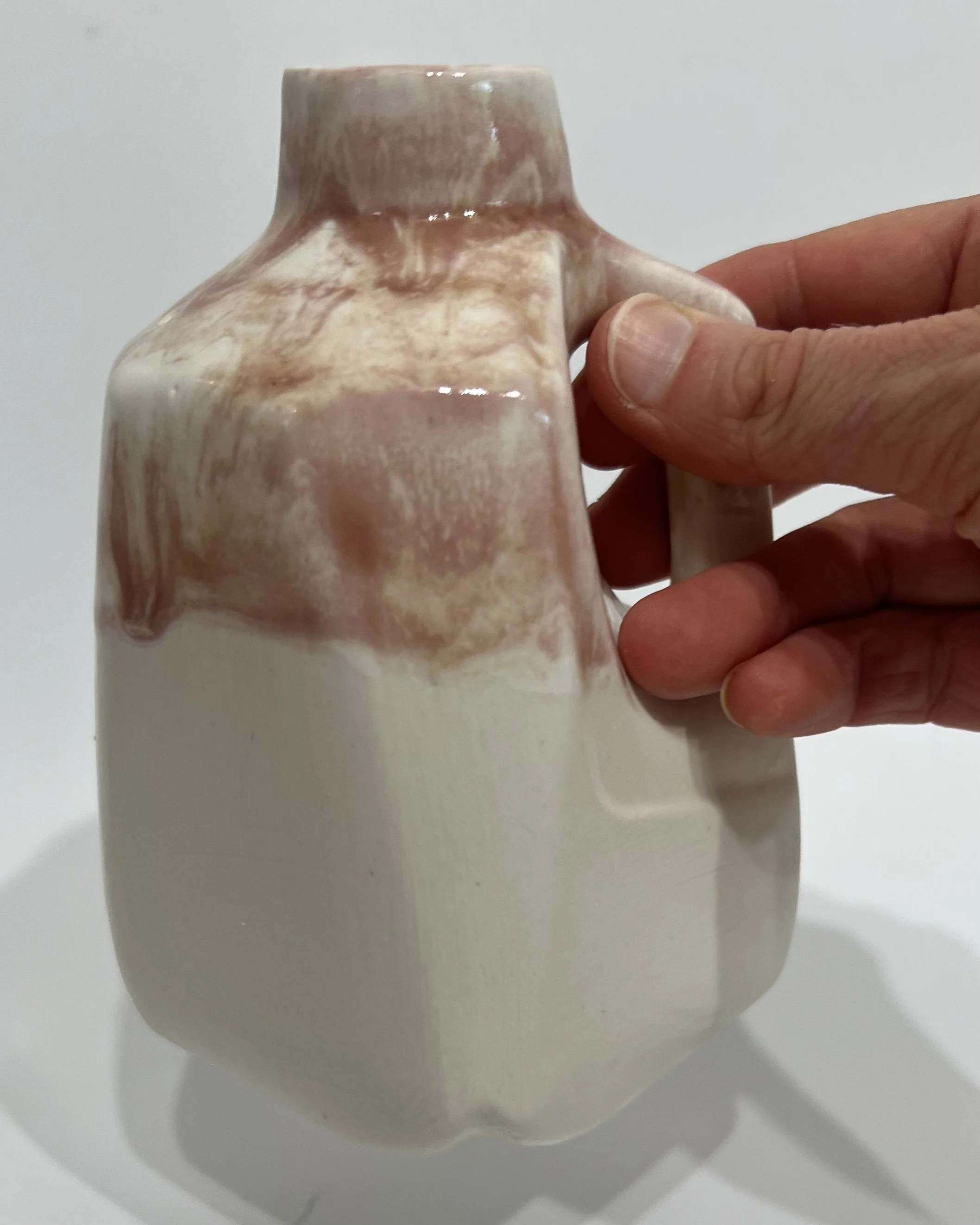 Hand holding porcelain jug to show scale and sculptural form
