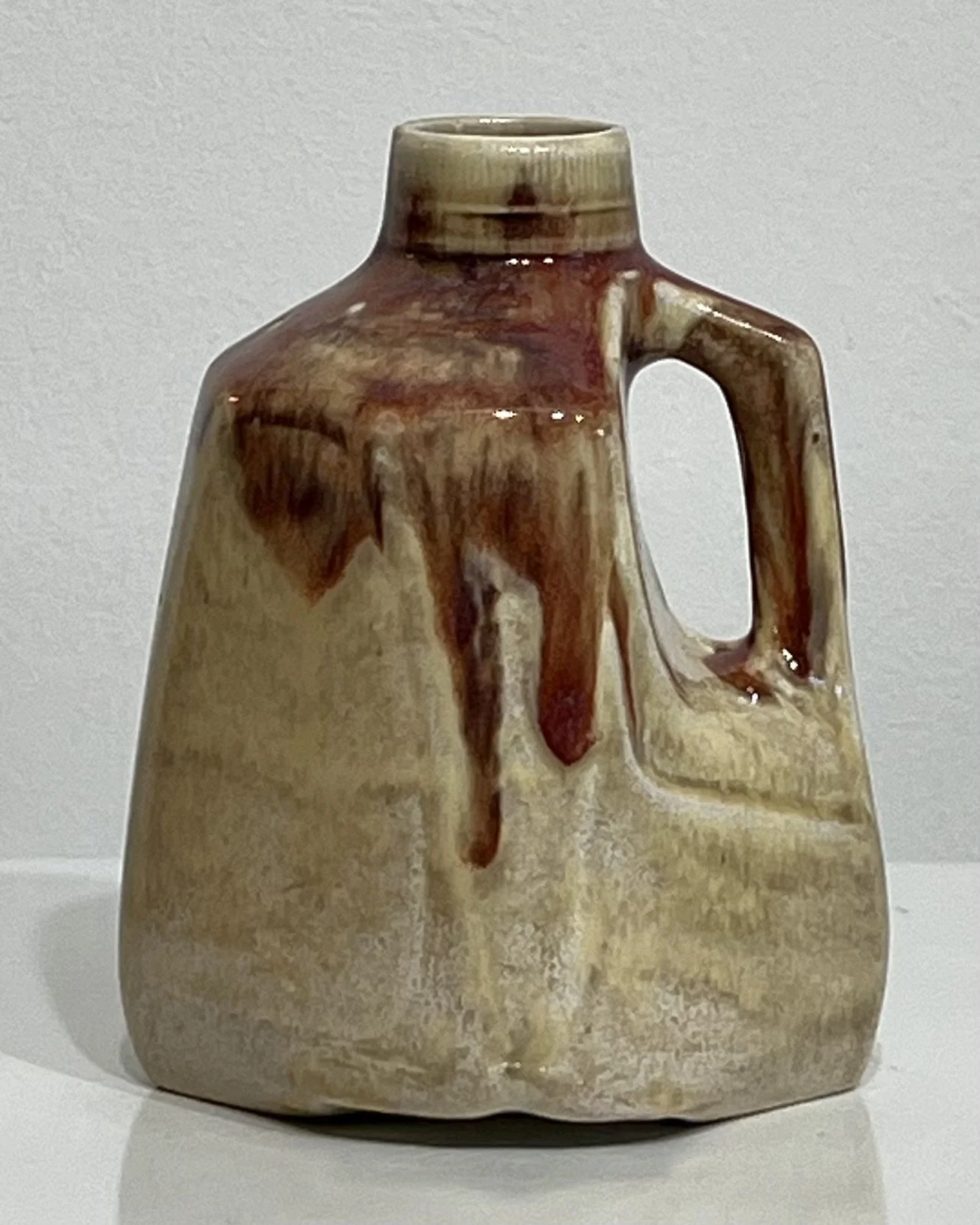 Front view of cream porcelain milk jug with deep burgundy Chun Plum glaze drips