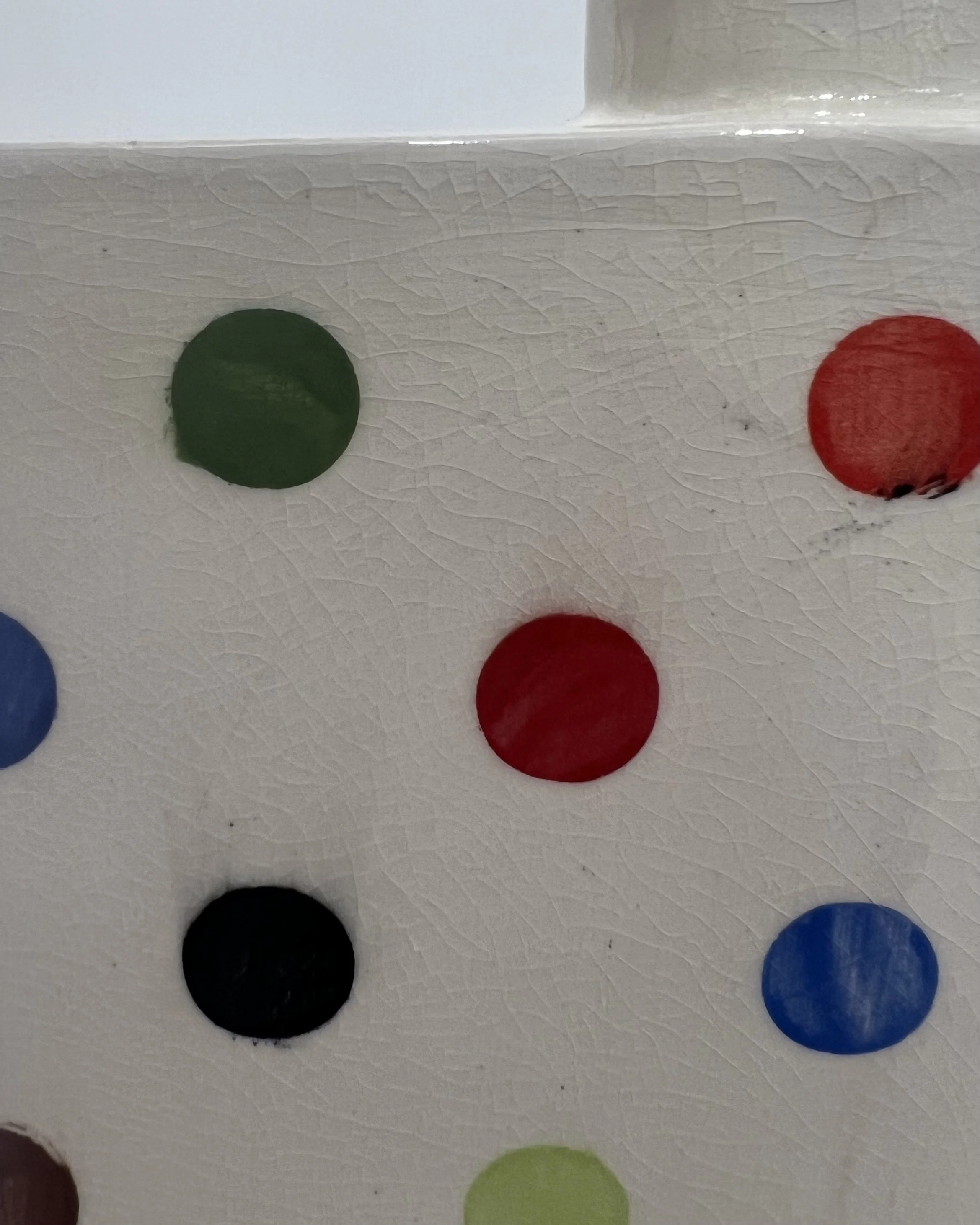 Close-up detail of colorful underglaze dots on white porcelain