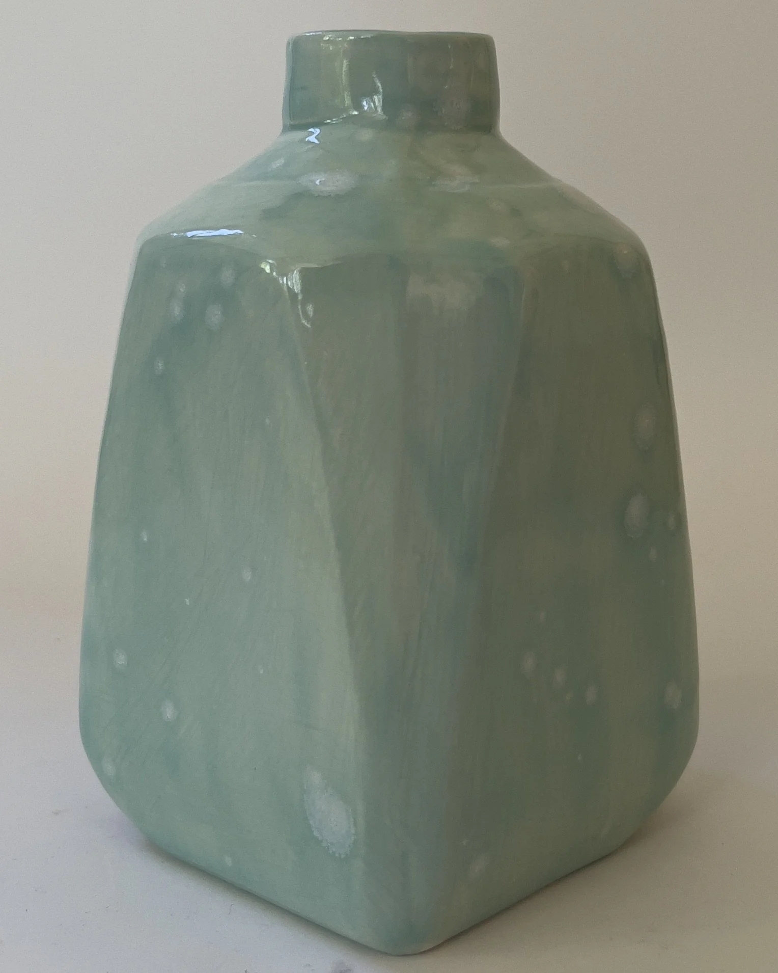 Back view of handmade ceramic milk jug with glossy celadon bloom glaze