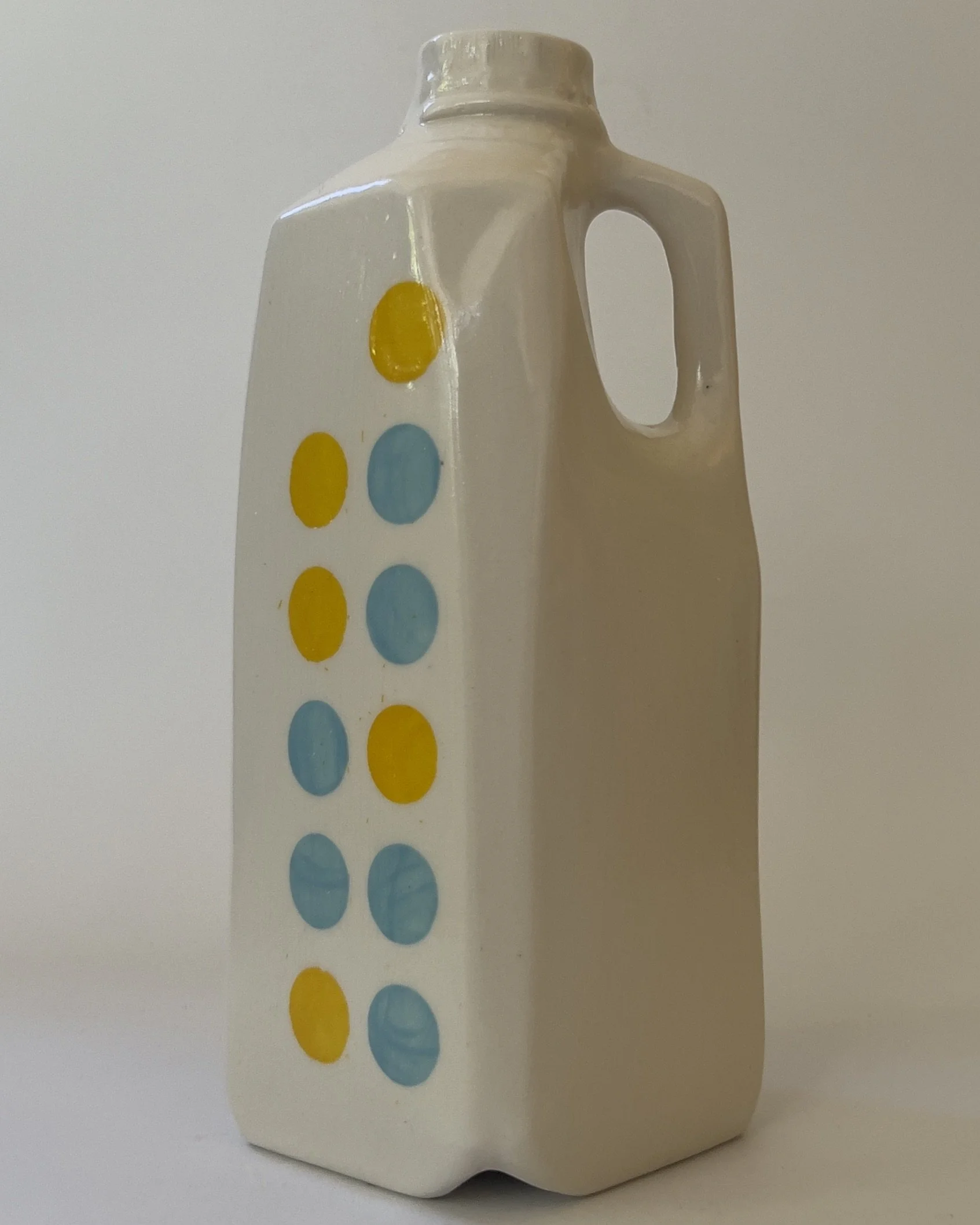 Angled front view of ceramic jug vase with glossy white glaze and colorful dots