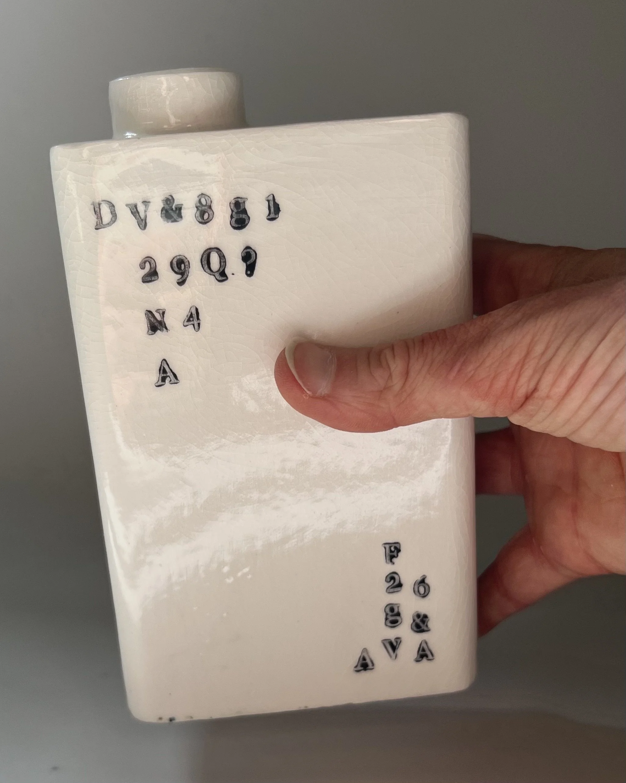 Hand holding a contemporary porcelain milk carton to show scale and proportions.