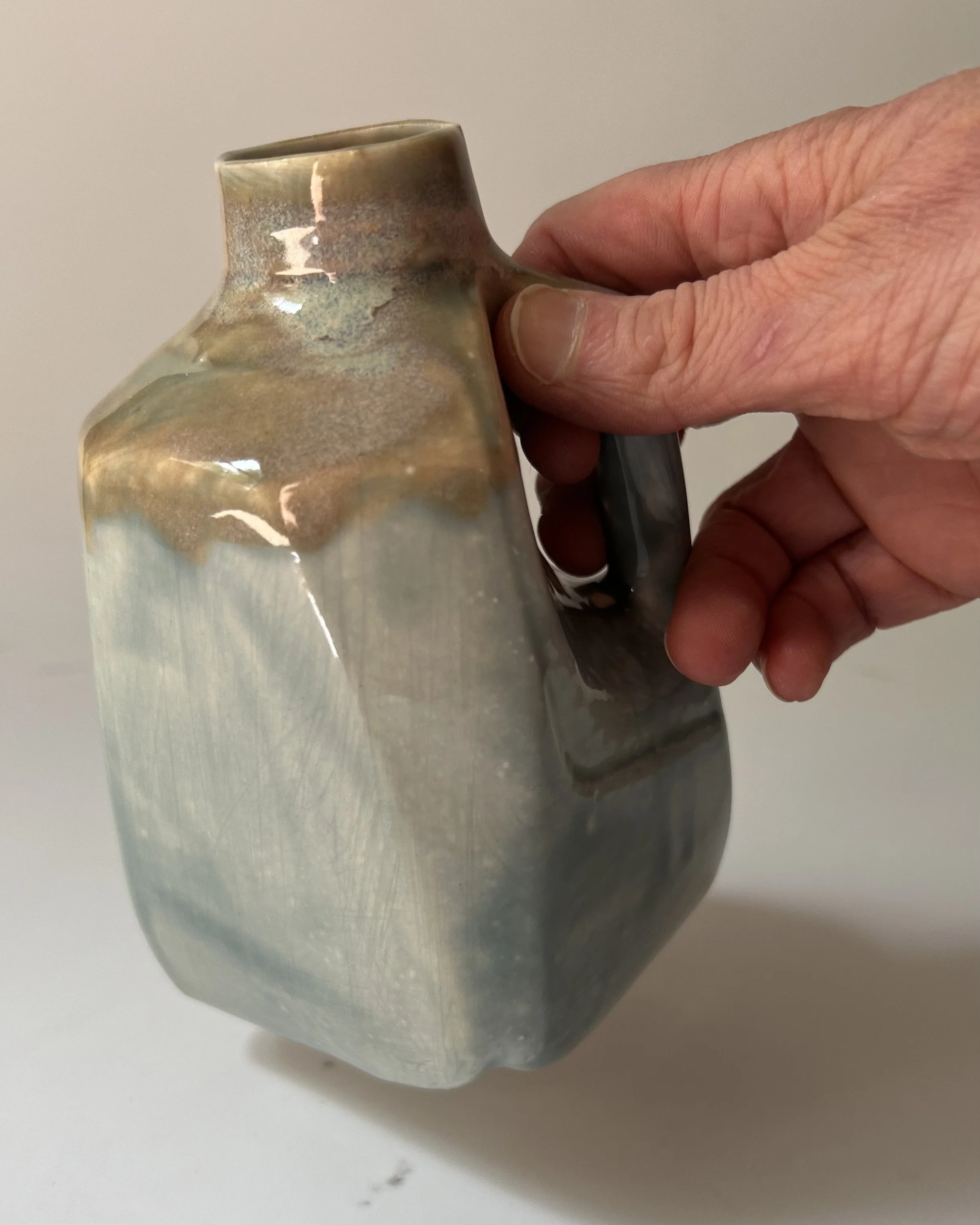Handmade porcelain milk jug shown in hand for scale.