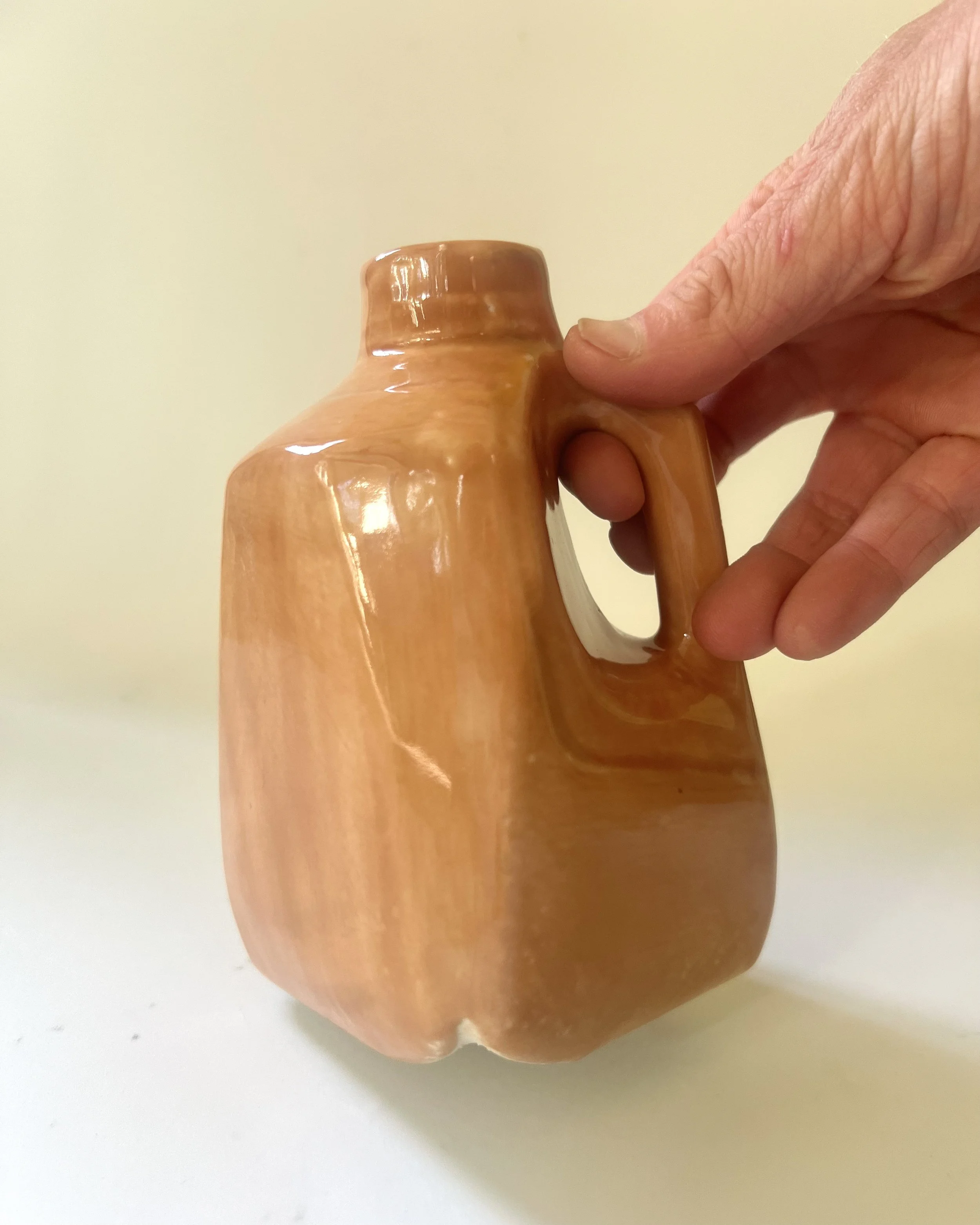 Hand holding a porcelain milk jug vase to demonstrate scale and size.