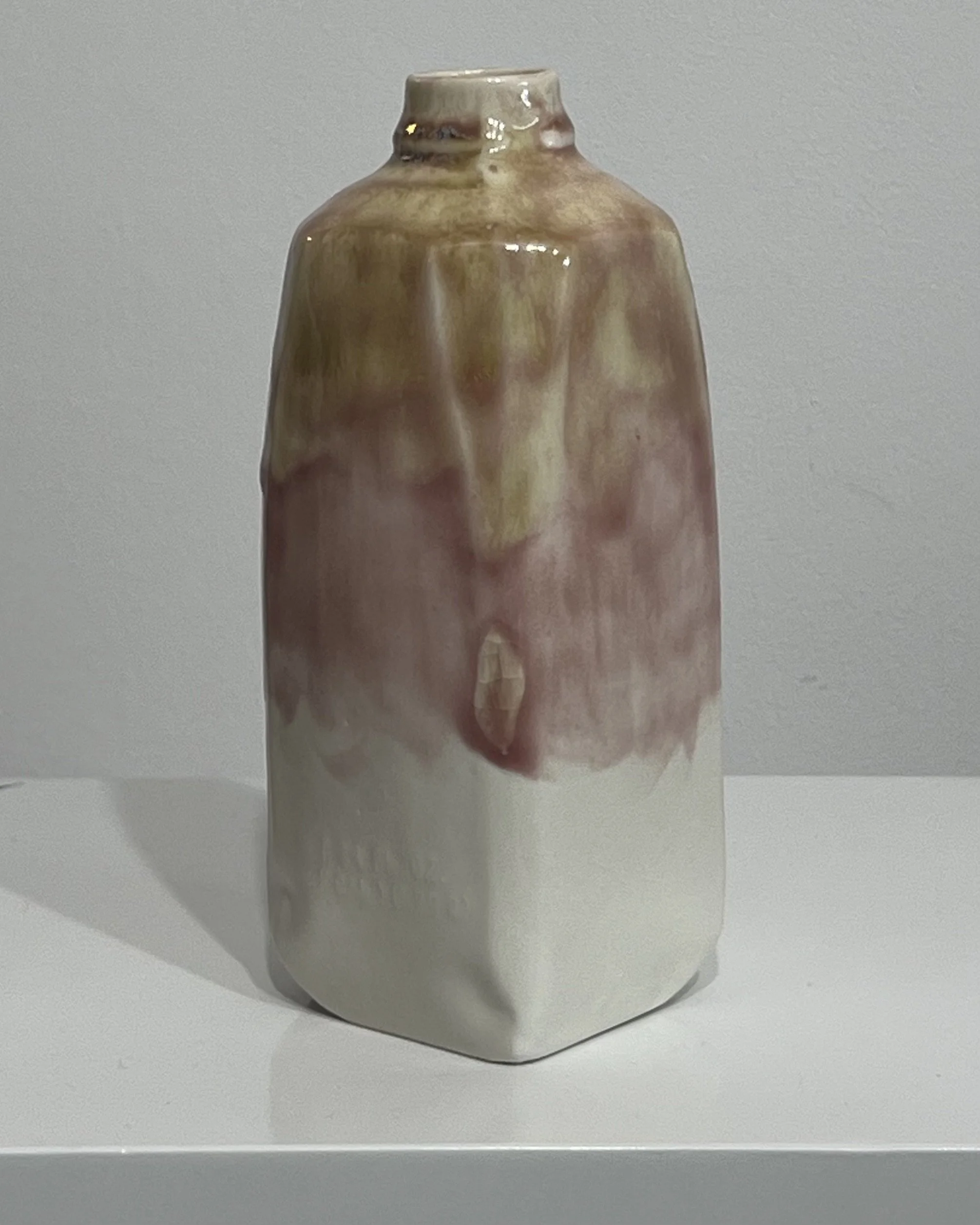 Back view of tall ceramic milk jug with olive green glaze flowing into soft pink and white.