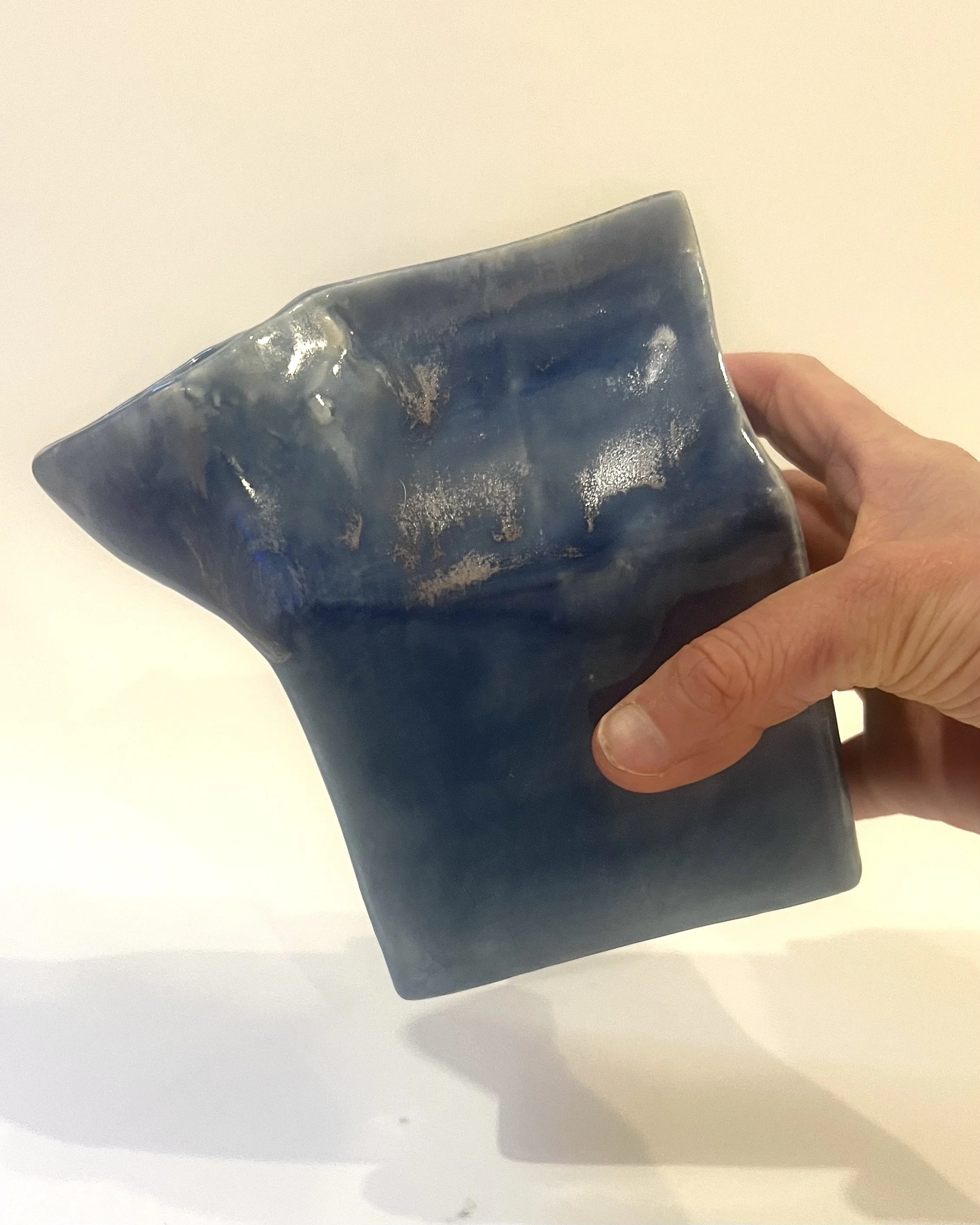 Hand holding Milk Carton 26.2 Blue Splatter porcelain vessel to demonstrate scale and size.