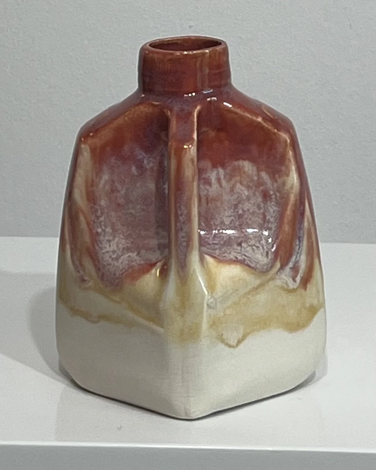 Side view of ceramic milk jug 26.80 showing flowing burgundy and golden glazes around its handle