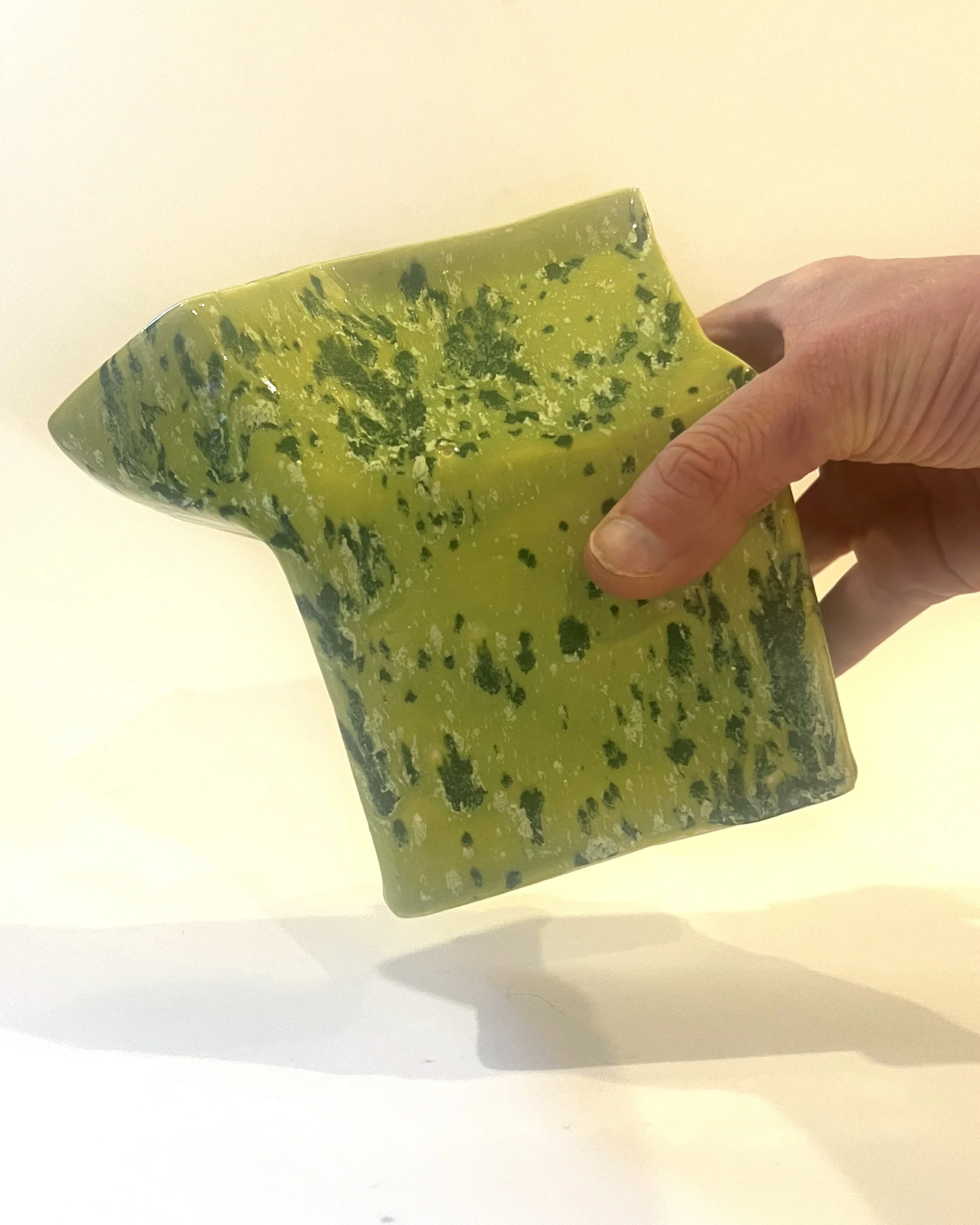 Hand holding porcelain milk carton sculpture for scale, finished in Lime Shower chartreuse glaze with green crystalline texture.