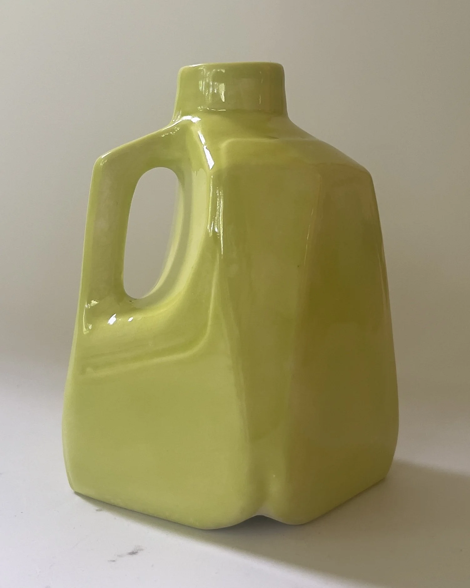 Three-quarter view of handmade ceramic Pear jug with glossy chartreuse glaze and curved edges.