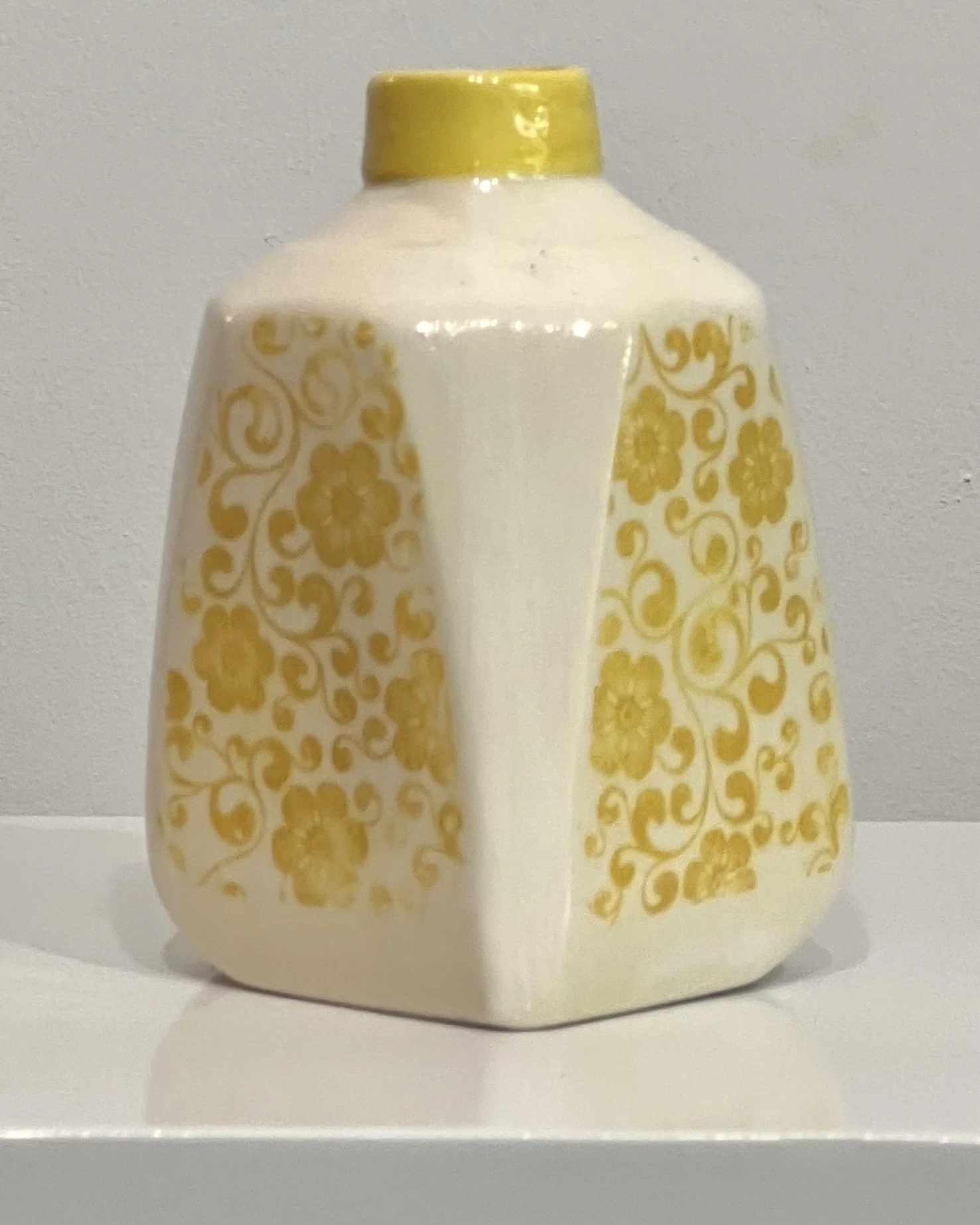 Left side view of a yellow floral porcelain milk jug with botanical transfer decoration.