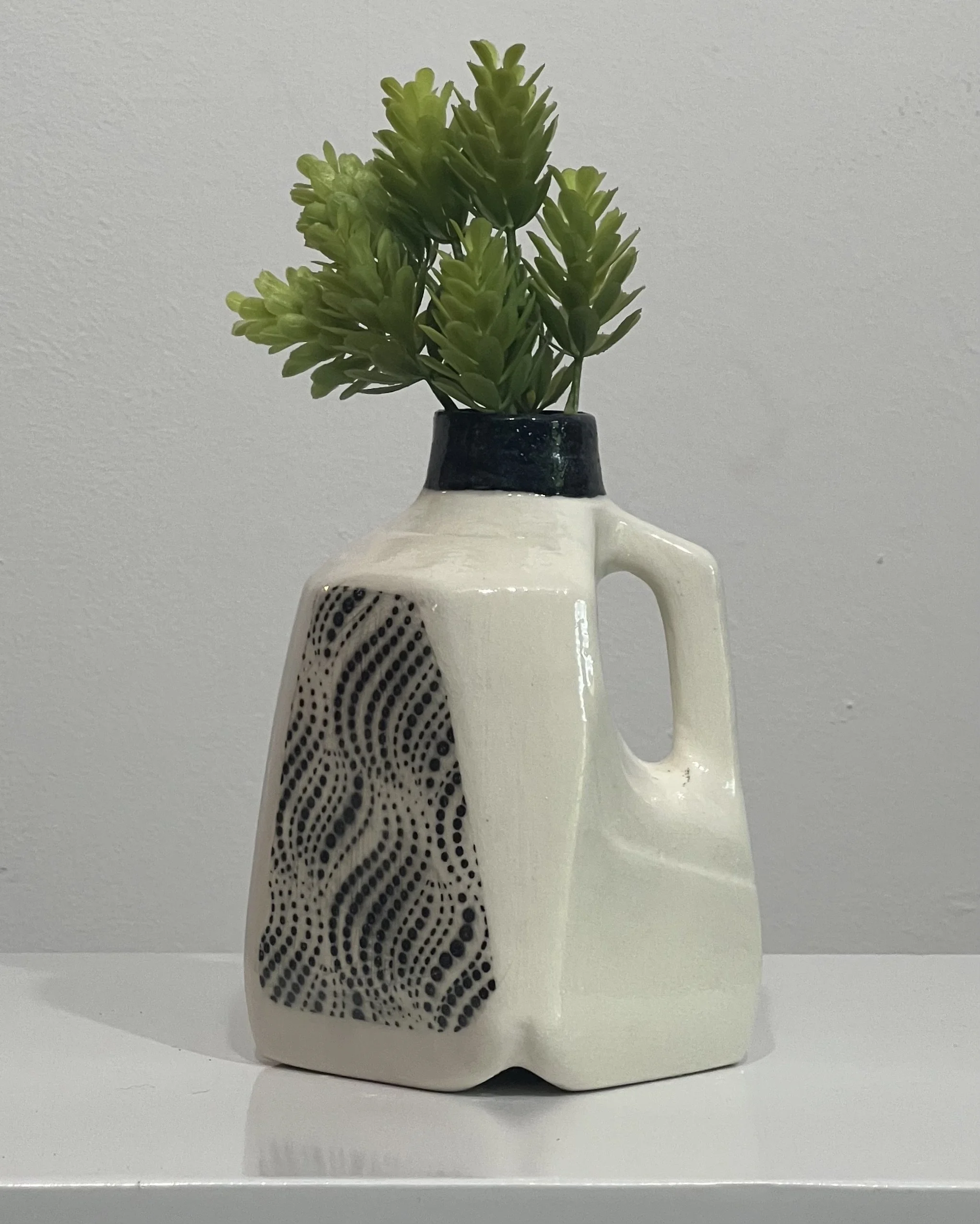Handcrafted porcelain milk jug vase with black dotted wave pattern, cream glaze, and dark blue neck.