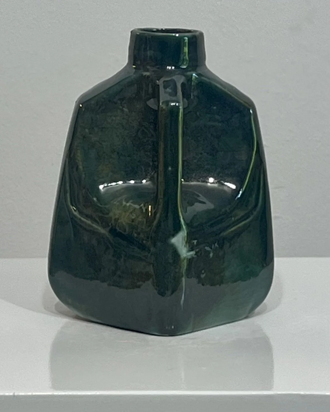 Rear view of porcelain milk jug vase highlighting integrated handle and atmospheric green Rainforest glaze.
