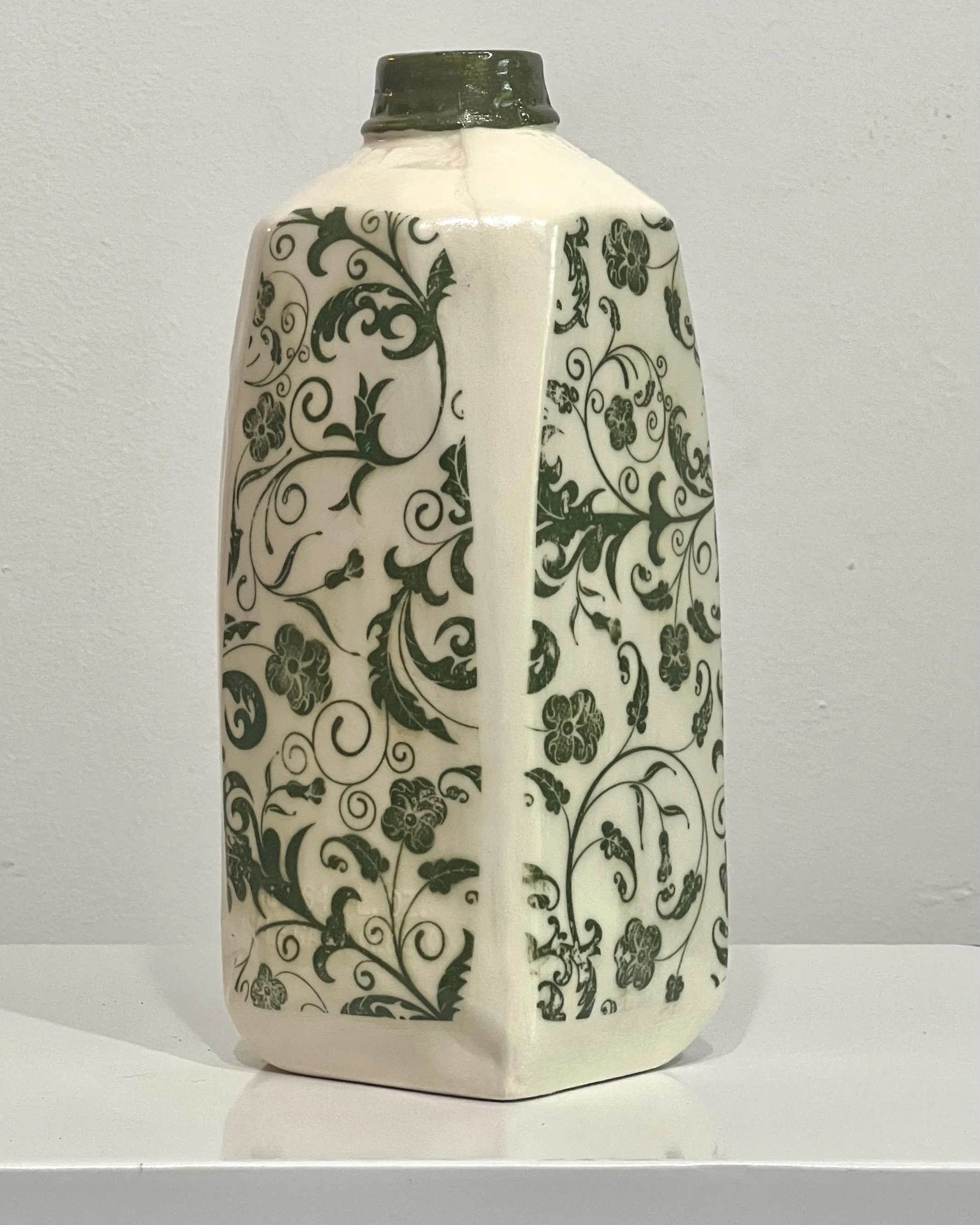 Left side view of a handcrafted botanical tall porcelain milk jug with green botanical transfer artwork.
