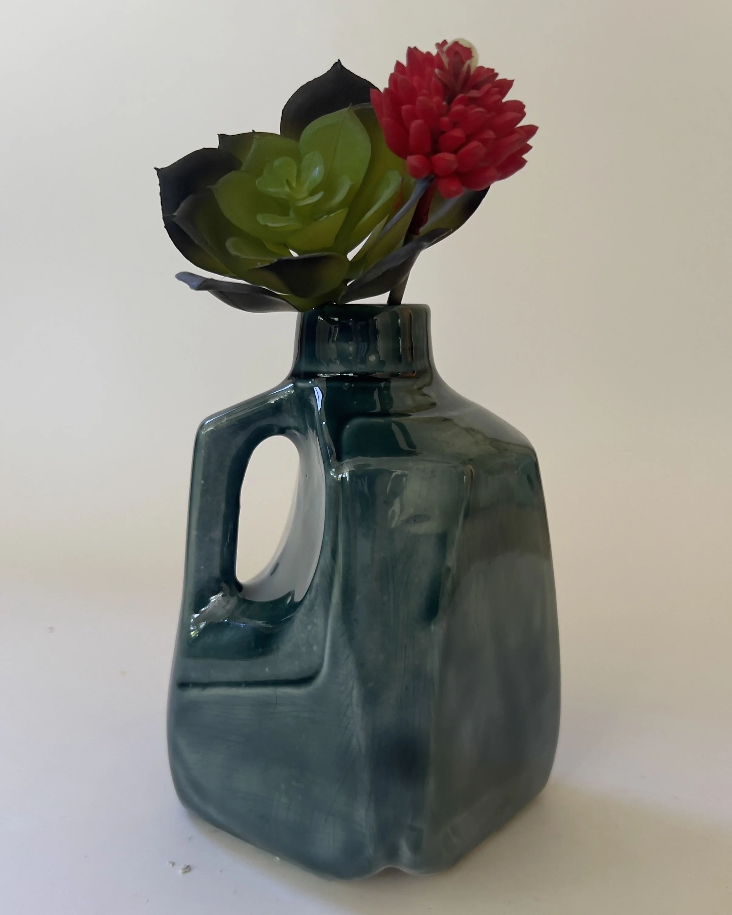 Handmade ceramic jug vase styled with flowers and succulent stems