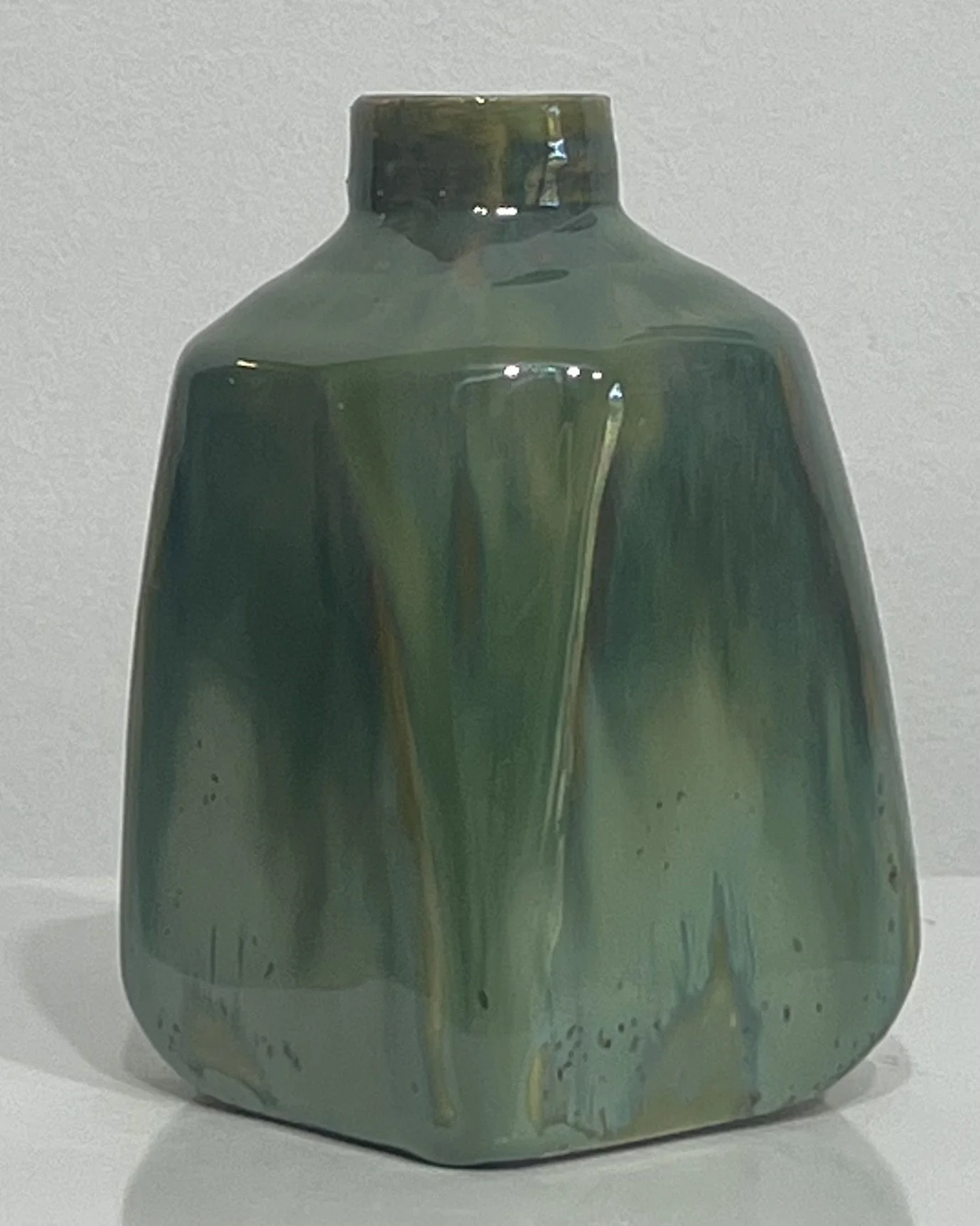 Left-side view of handmade green ceramic milk jug with glossy glaze and integrated handle.
