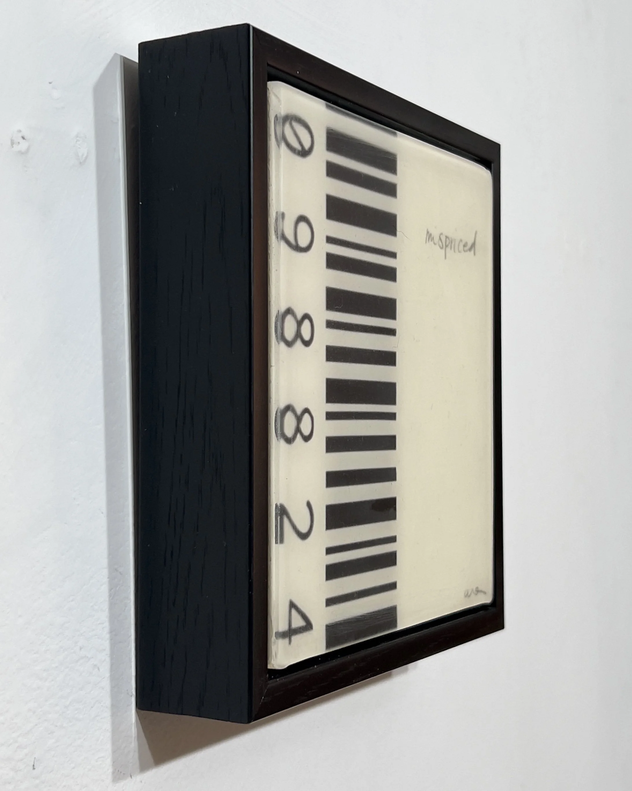 Angled view of Mispriced by Alissa Van Atta, a 6 by 6 inch original acrylic, collage and resin artwork on wood, presented in a deep black frame.