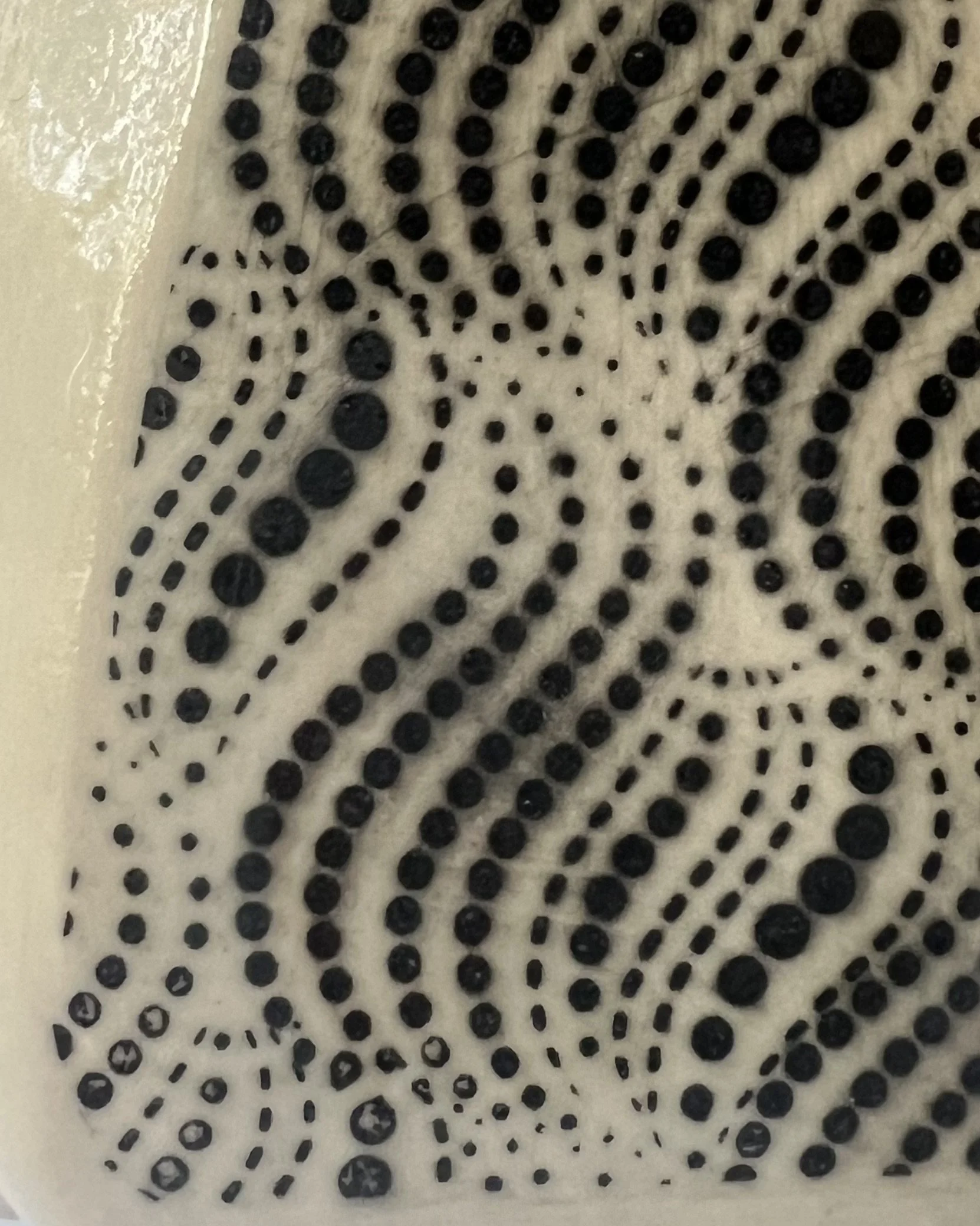 Detail of black dotted wave pattern on handcrafted porcelain milk jug.