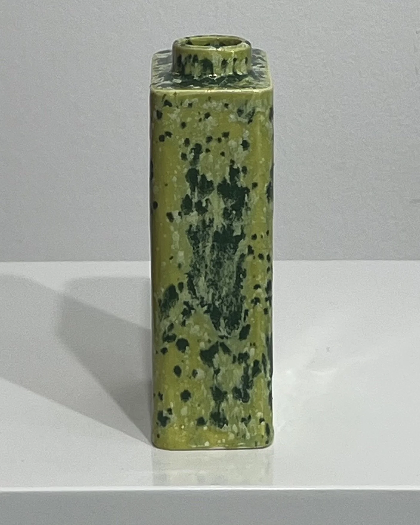 Narrow side of handmade porcelain carton showing its slim rectangular profile and mottled green glaze