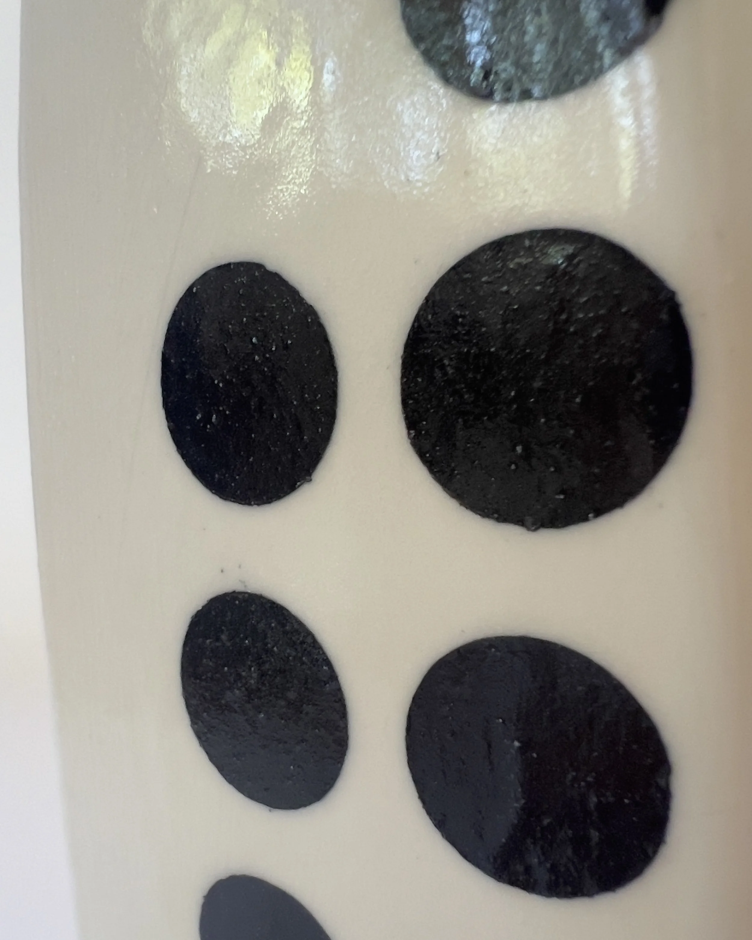 Close-up detail of glossy black dot pattern on handmade ceramic vase