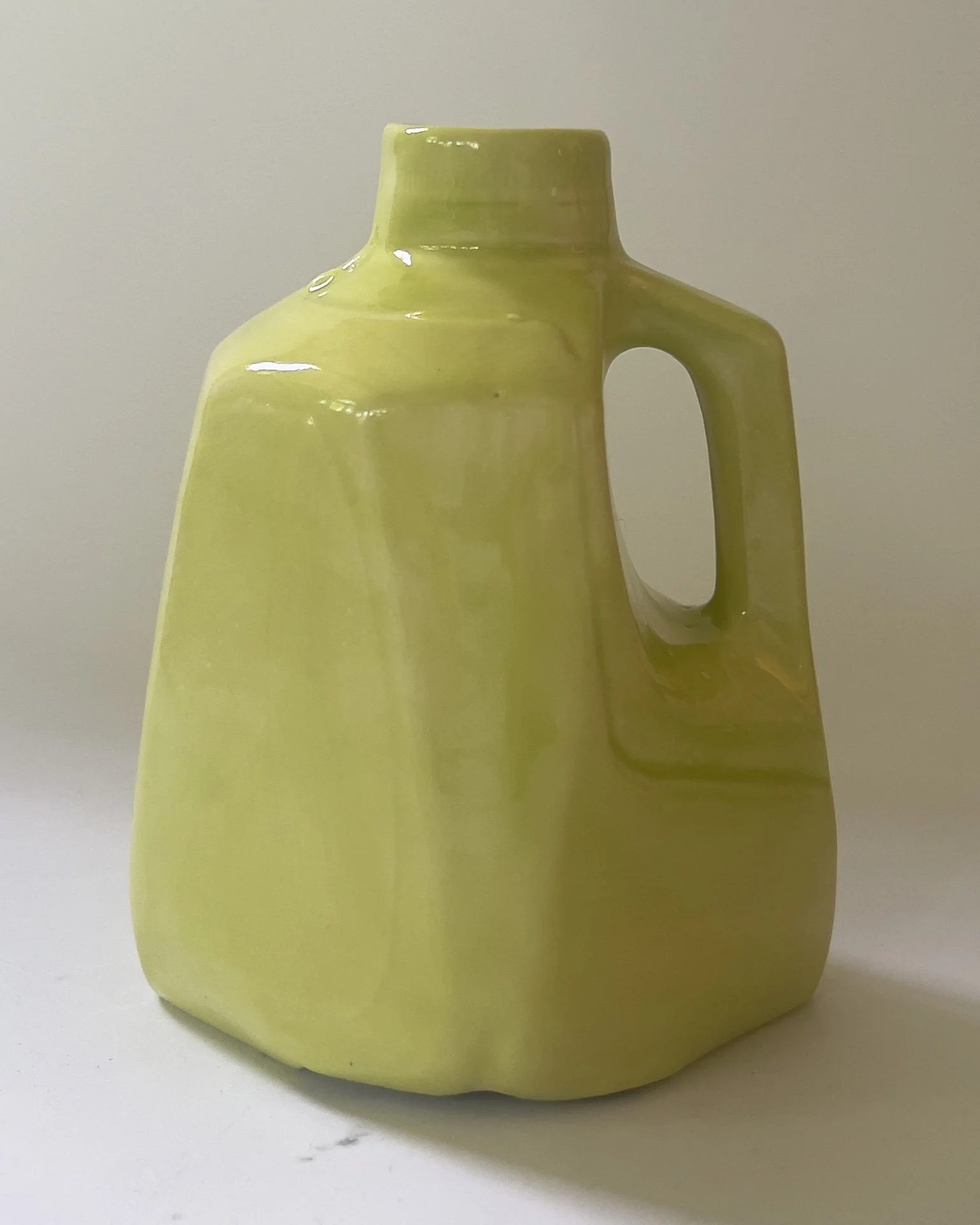 Handmade ceramic jug in luminous Pear glaze with softened sculptural form, front view.