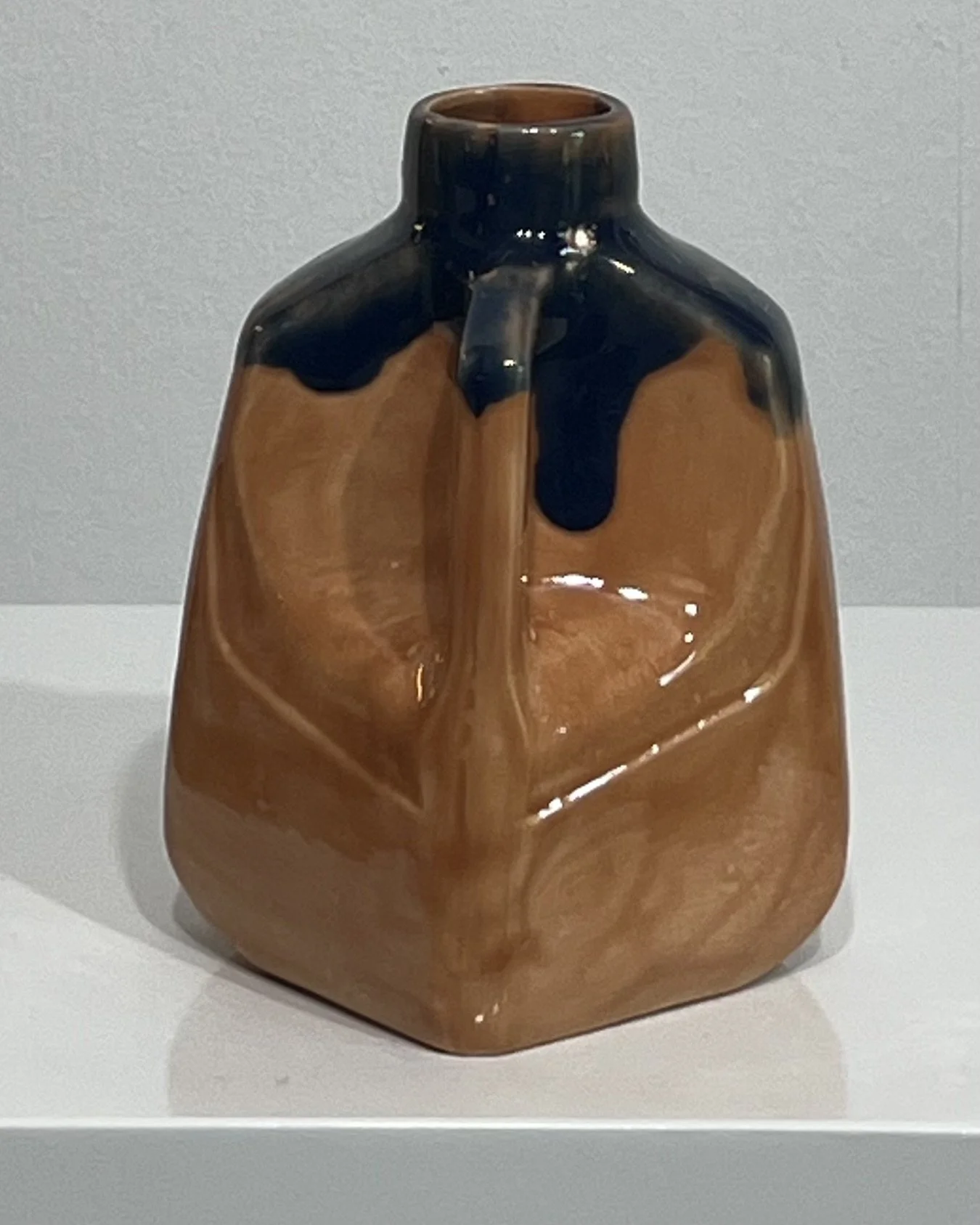 Angled view of porcelain milk jug vase with warm brown and deep blue glaze