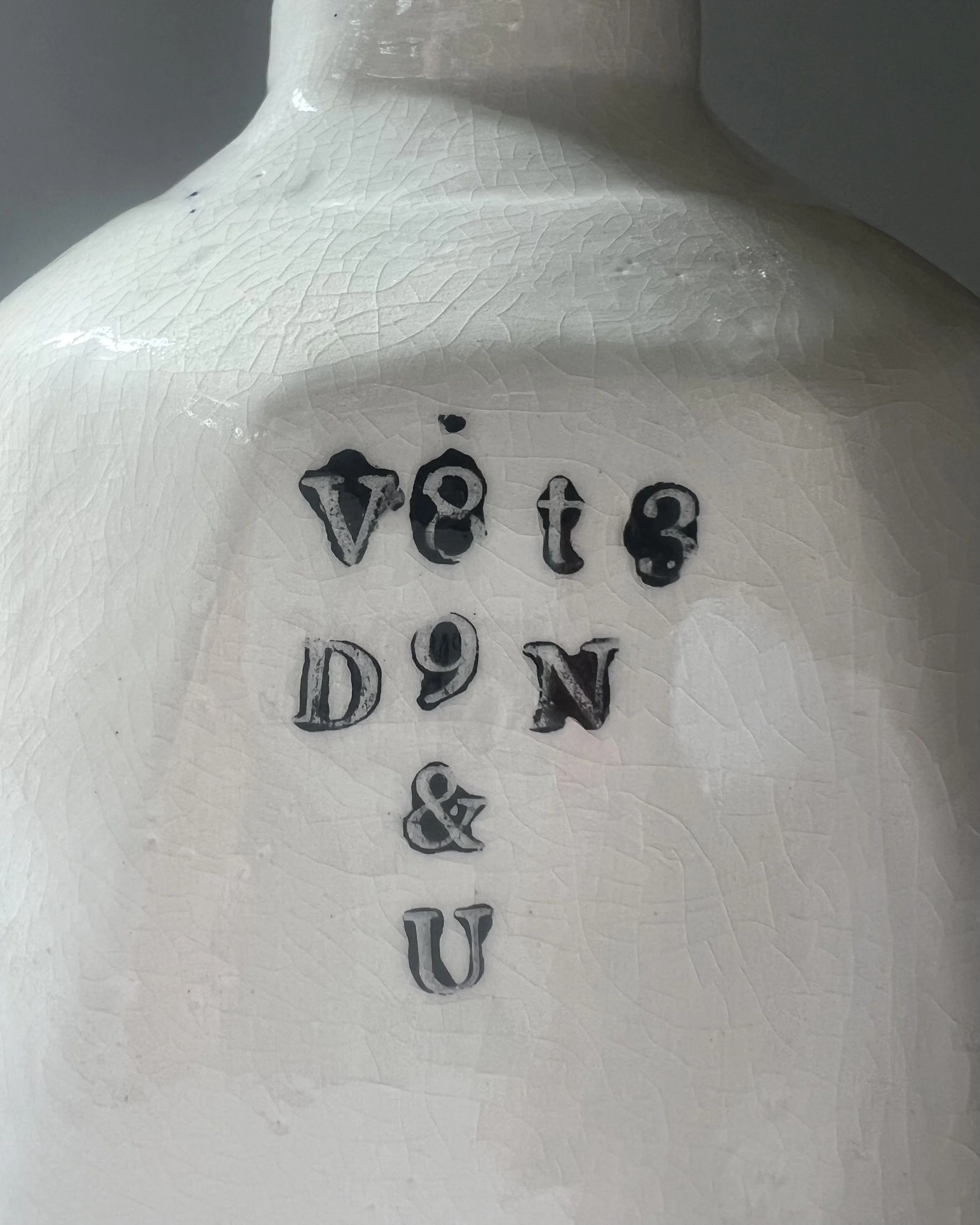 Close-up of impressed black typography on the surface of a handbuilt white porcelain milk jug.