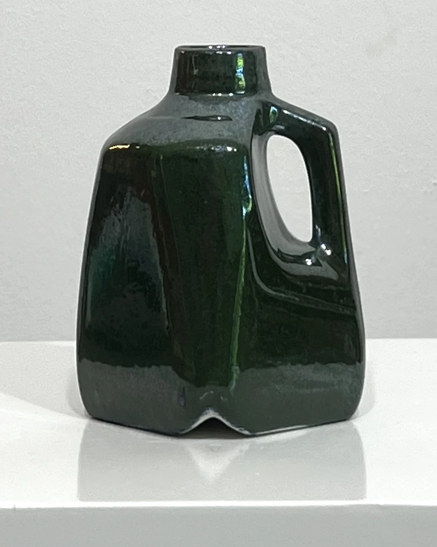 Front view of porcelain milk jug 26.48 in glossy Junebug glaze with integrated side handle.