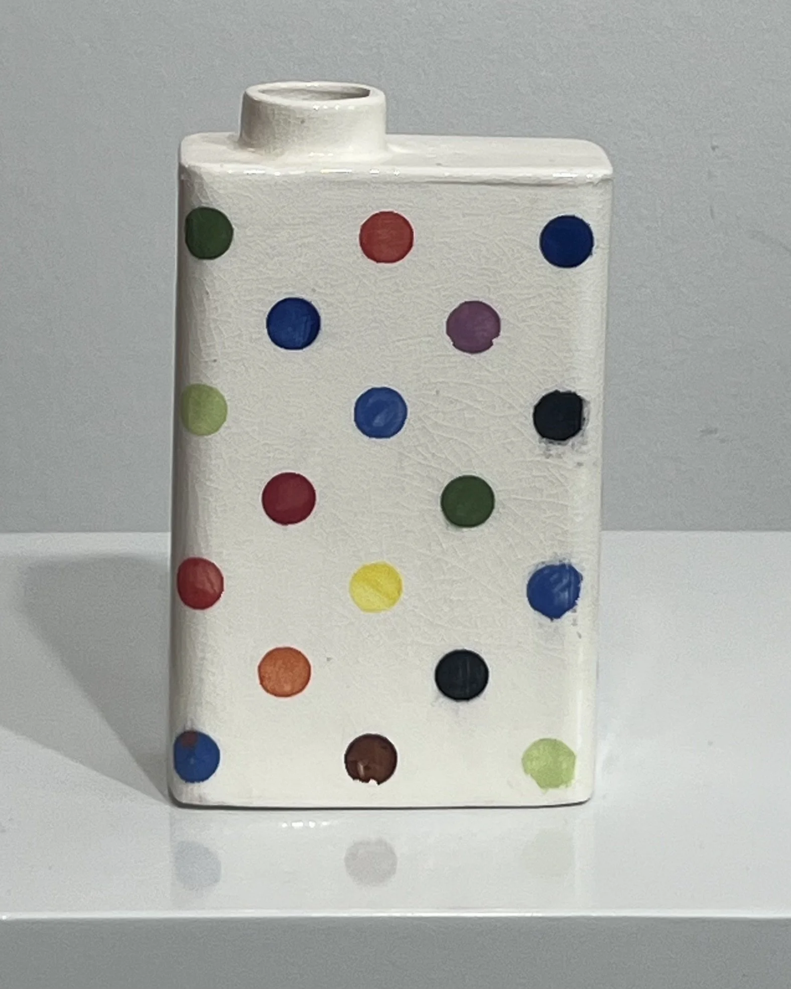 Front view of white porcelain carton vase with multicolored polka dots