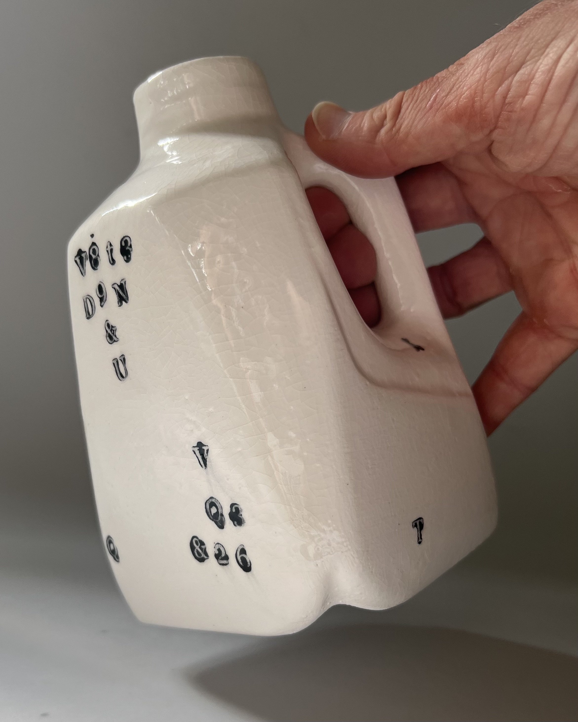 Hand holding a contemporary porcelain milk jug to show scale and proportions.