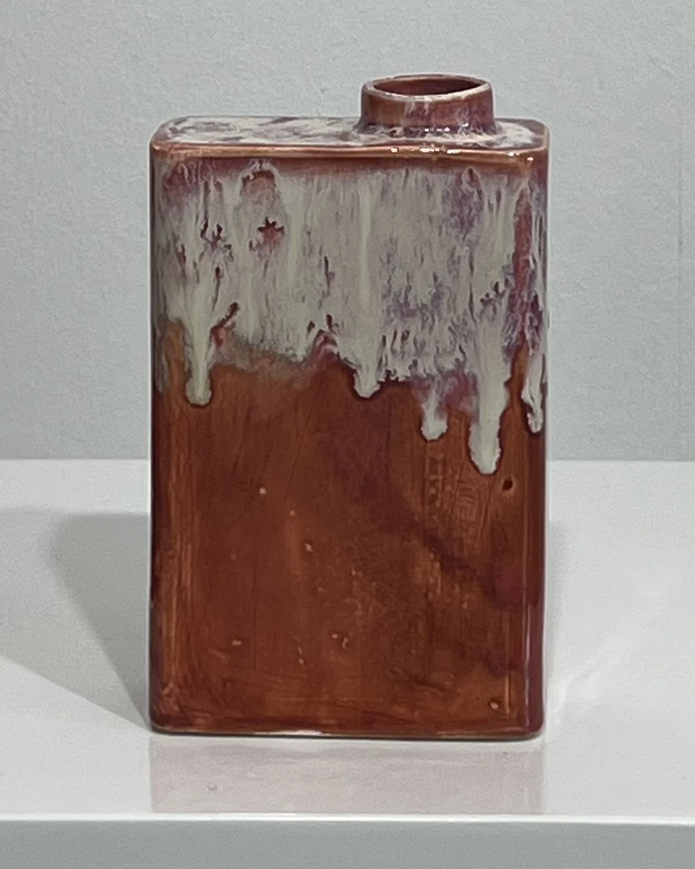 Handbuilt ceramic carton sculpture with plum, cream and rust-red flowing glaze surface