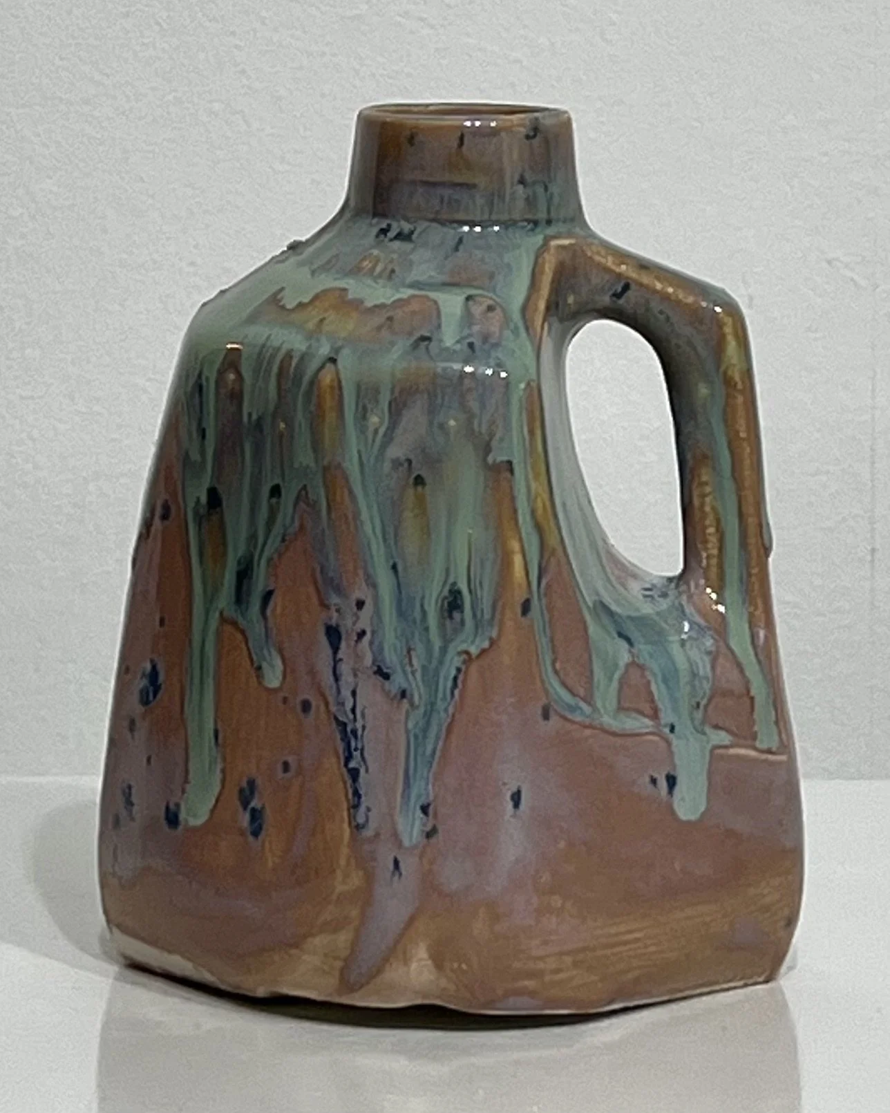 Front view of handmade pink and turquoise porcelain milk jug with flowing glaze details