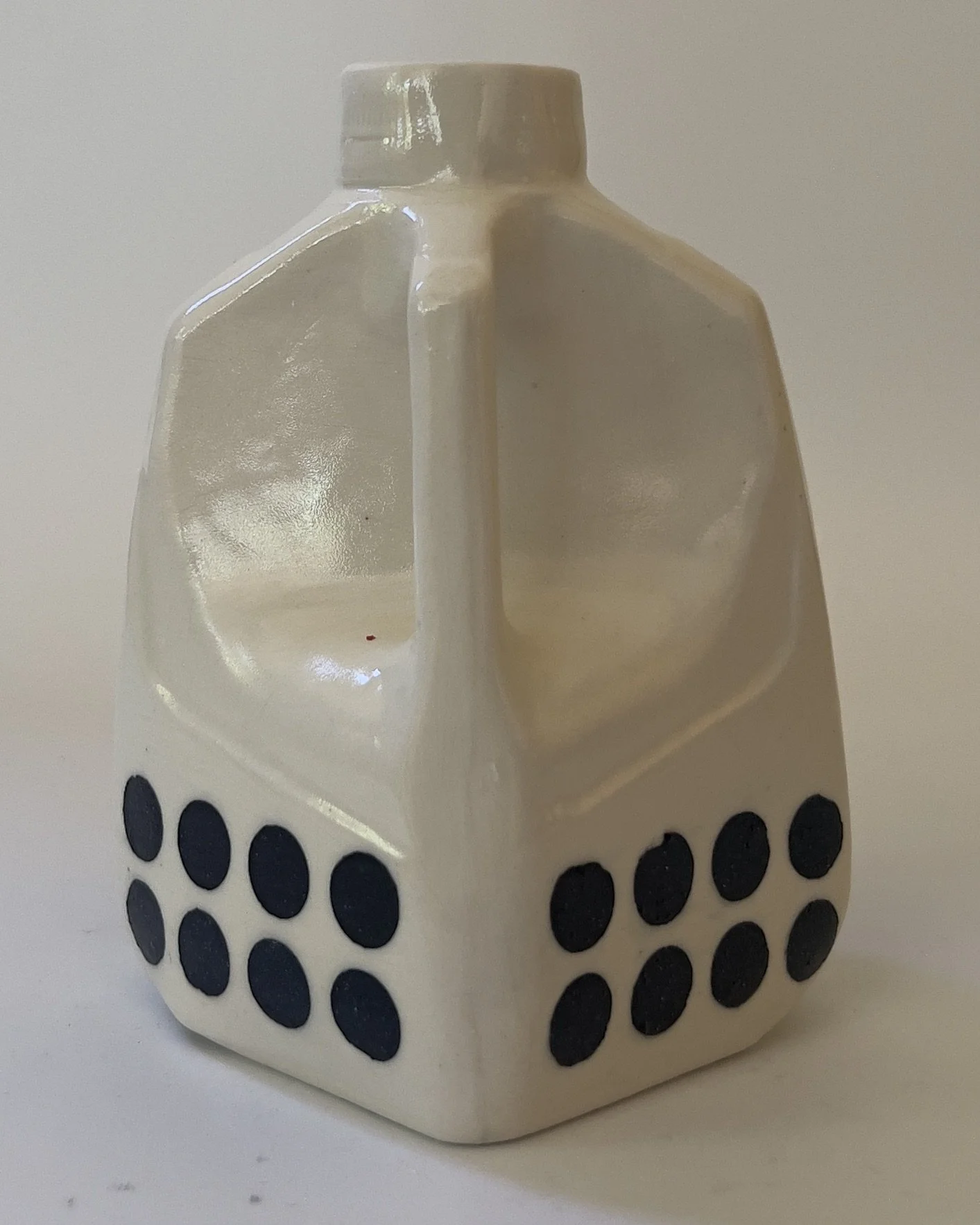 Side view of ceramic sculptural milk jug with inward dimpled form