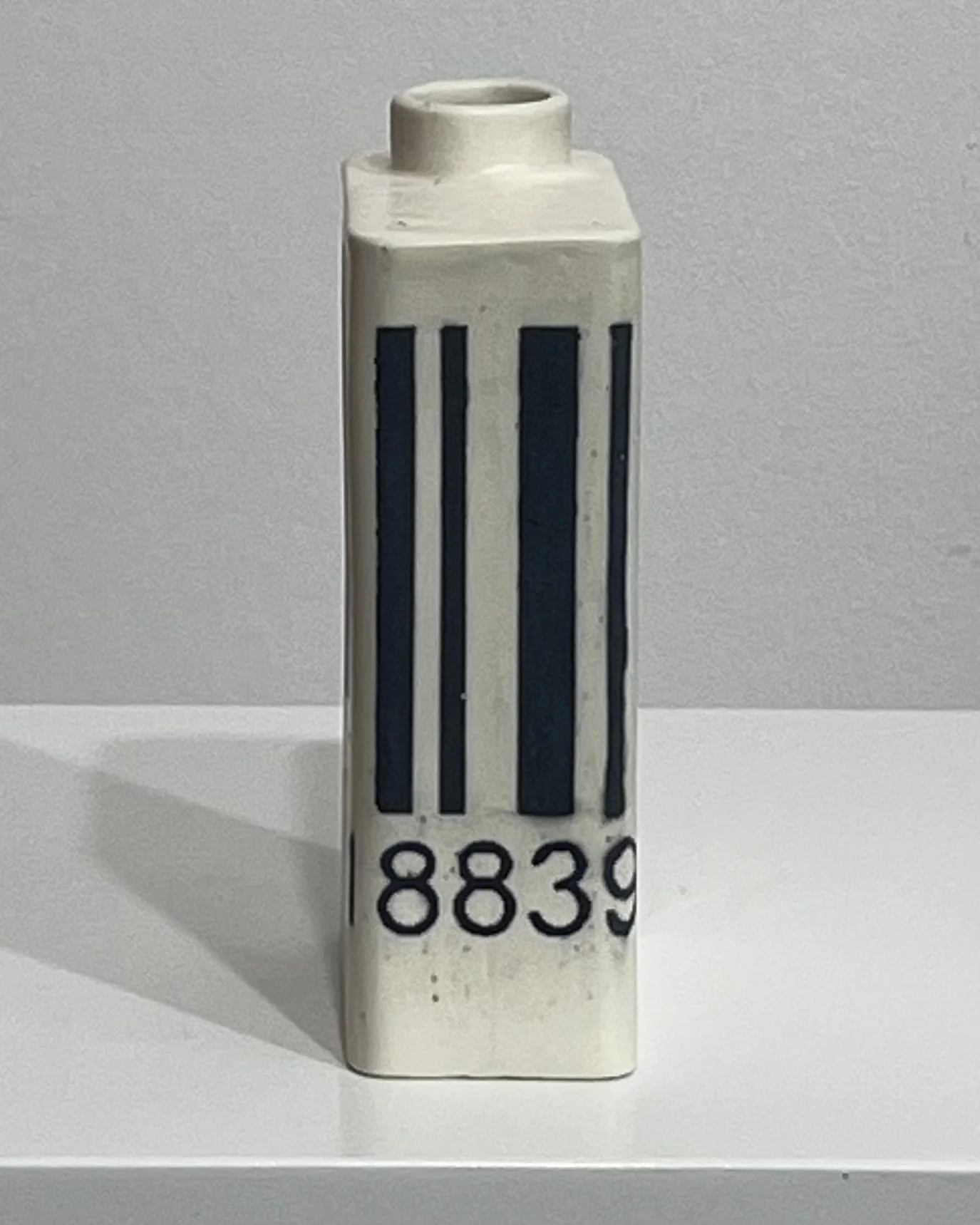 Angled view of porcelain barcode milk carton showing front and side design