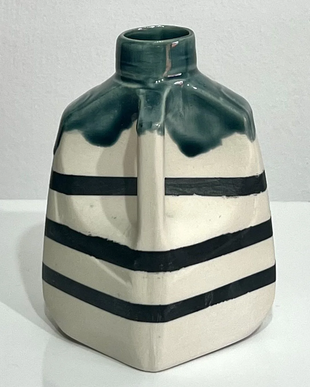 Right-handle view of porcelain milk jug No. 26.142, featuring dark horizontal stripes, a squared white body, small spout, and rich green glazed top.