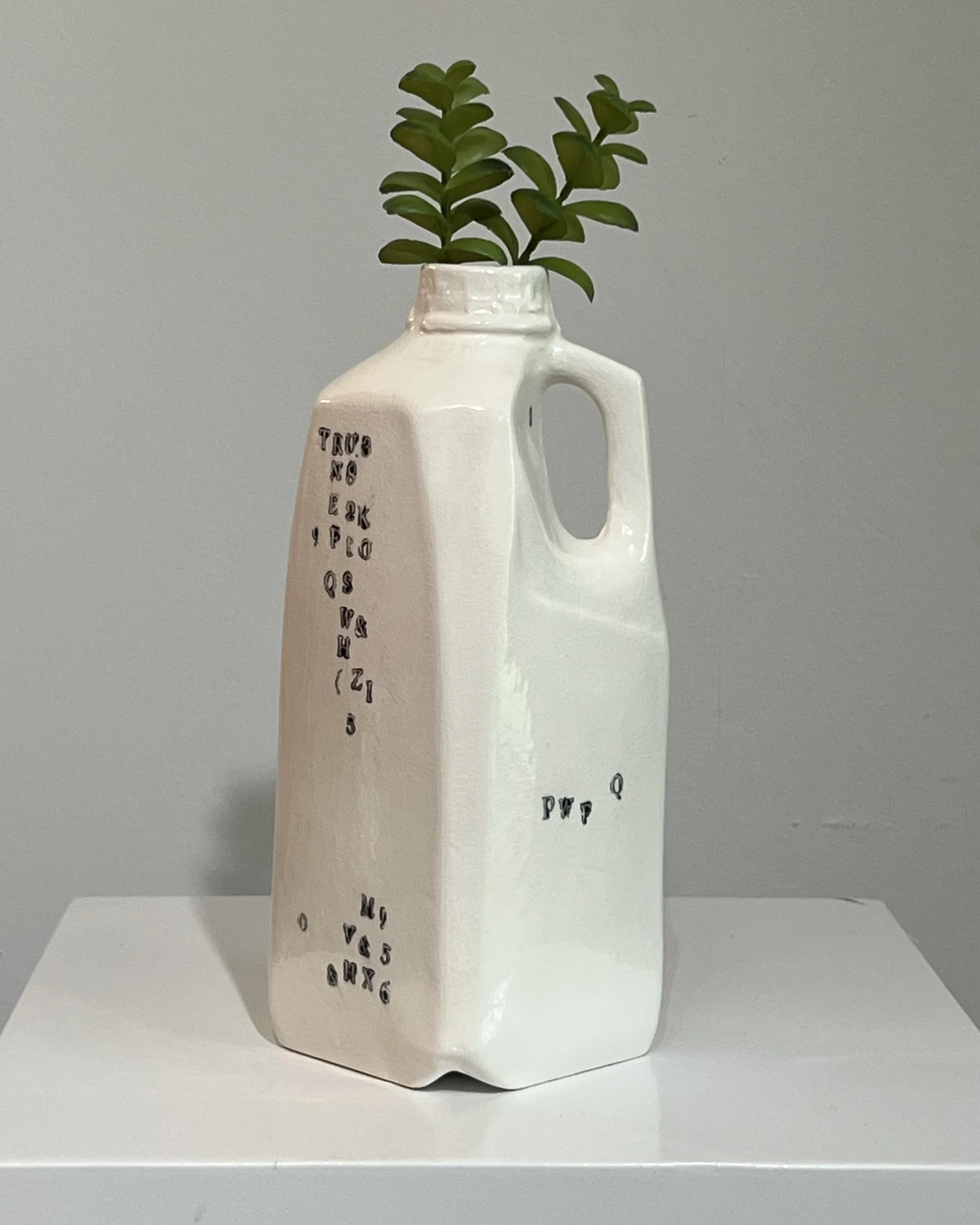 Handbuilt tall white porcelain milk jug from Alissa Van Atta's Type Series featuring black typographic impressions and green botanical stems.