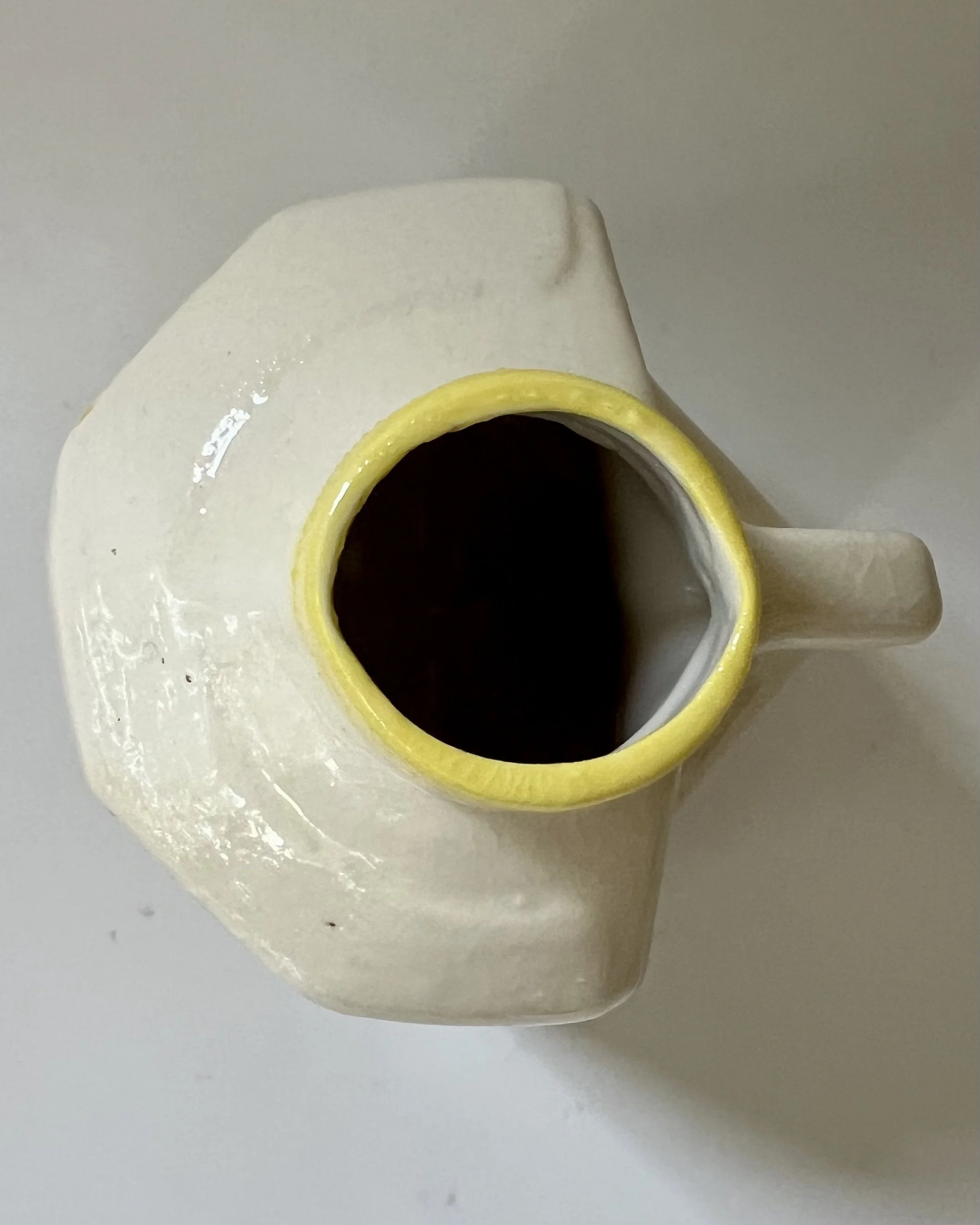 Top view of a handcrafted yellow floral porcelain milk jug showing the porcelain opening and interior.