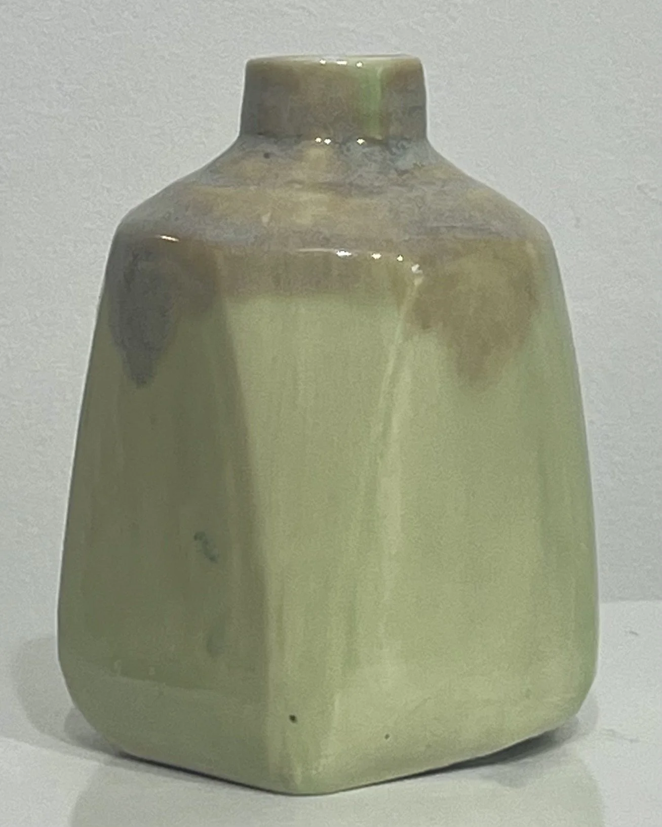Left-side view of handmade sage-green ceramic milk jug featuring flowing glaze details.