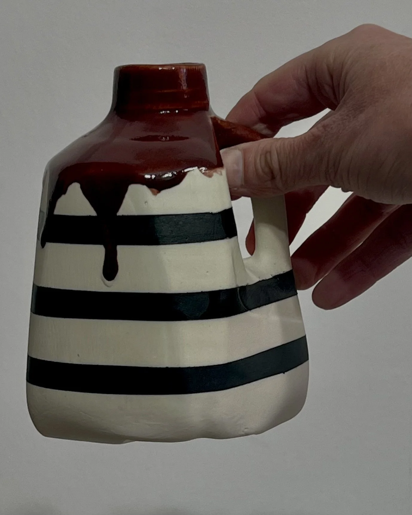 Hand holding porcelain milk jug No. 26.141 by Alissa Van Atta to demonstrate the small sculptural vessel's size and proportions.