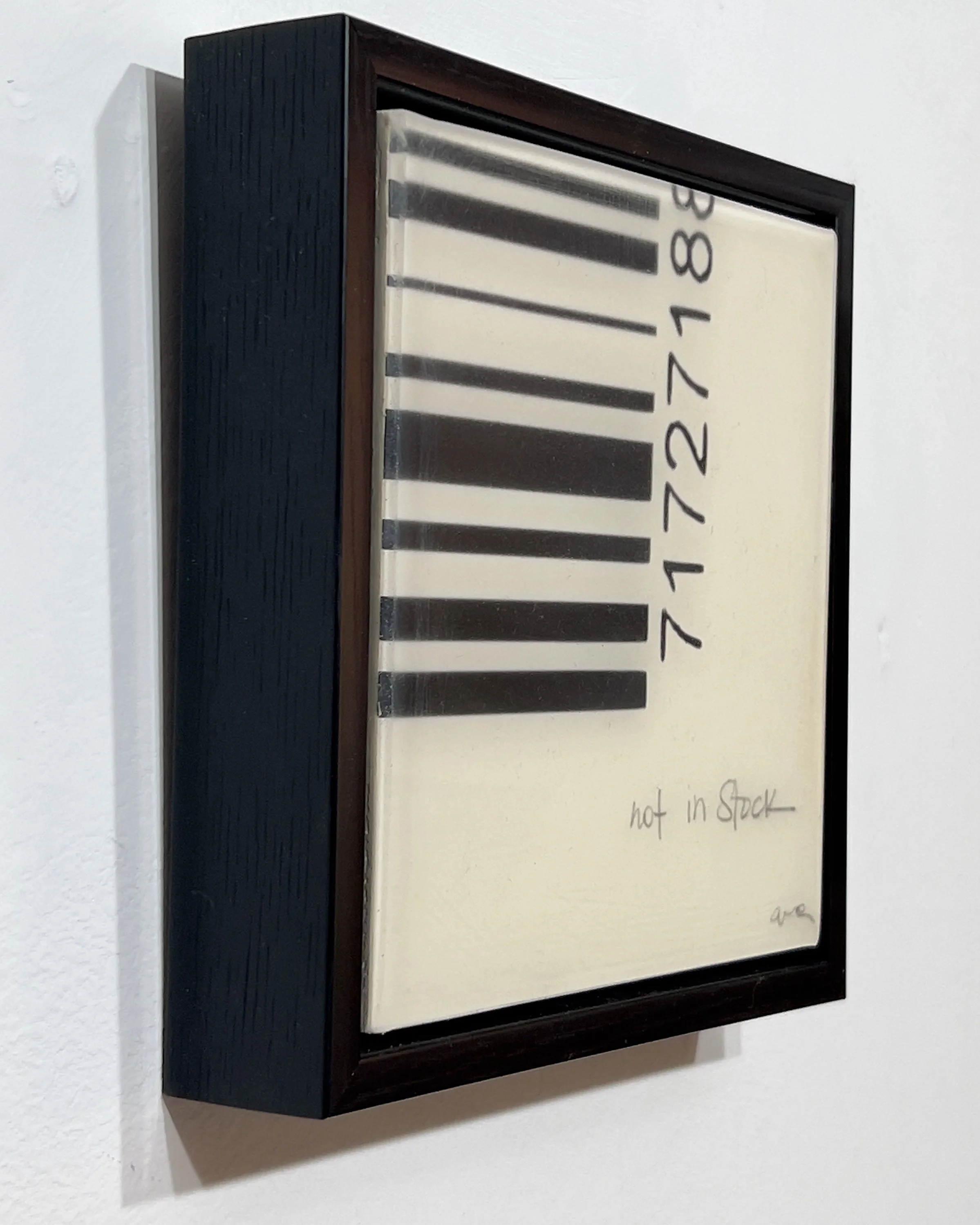 Angled view of Not in Stock by Alissa Van Atta, original 6 by 6 inch resin, acrylic and collage artwork on wood in a deep black frame.