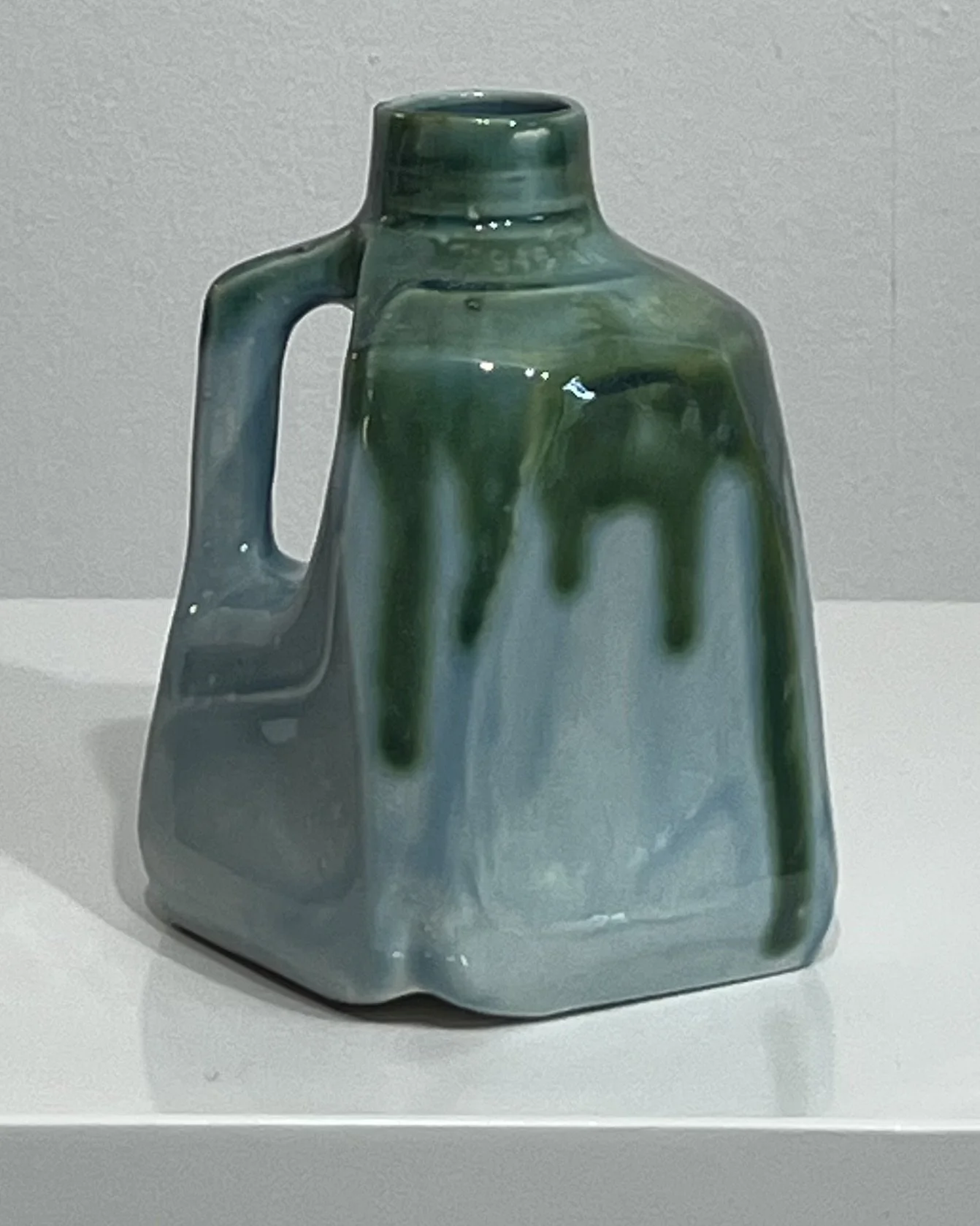 Side view of Lagoon and Seaweed ceramic milk jug vase showing the sculpted handle and flowing green glaze.