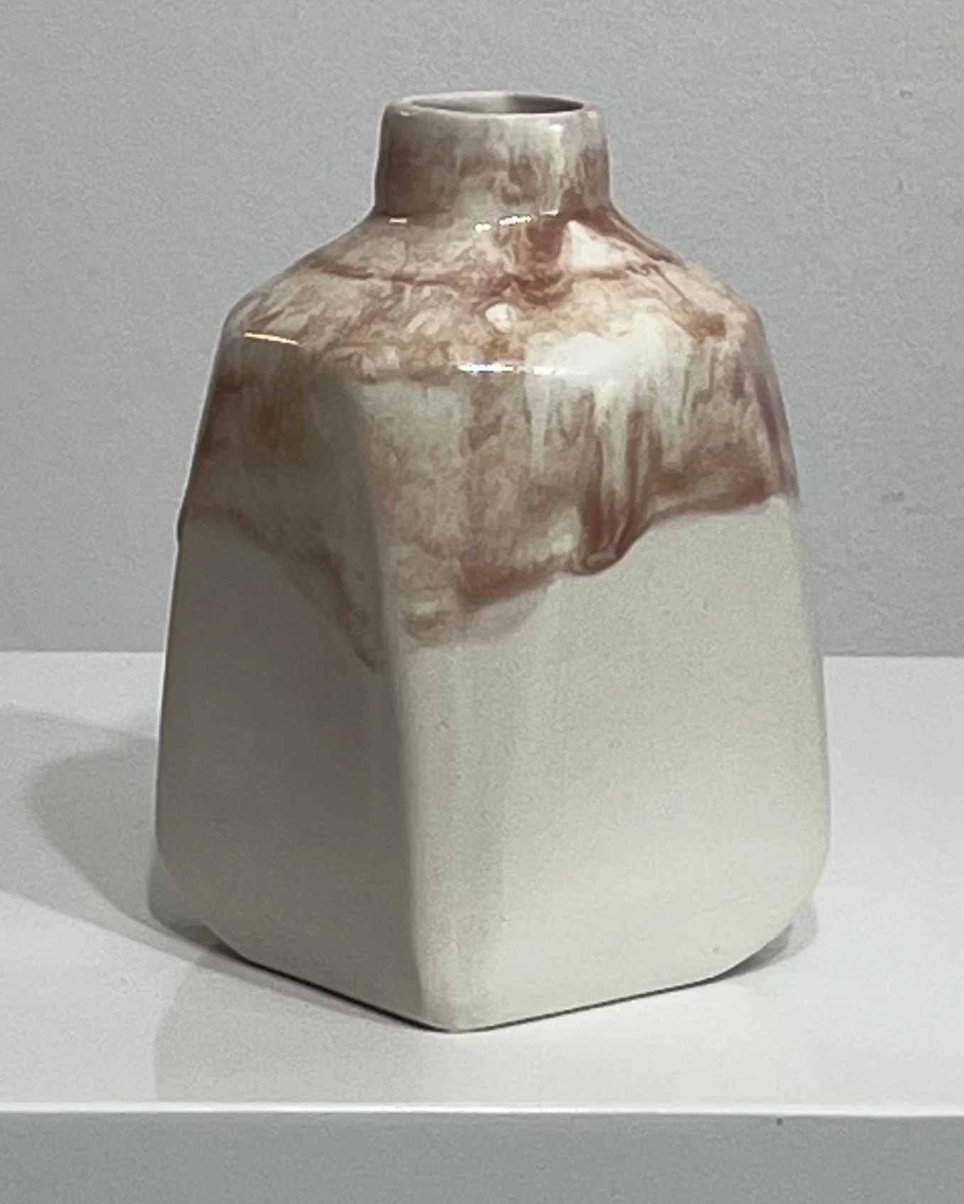 Back view of porcelain jug with creamy white body and painterly plum glaze
