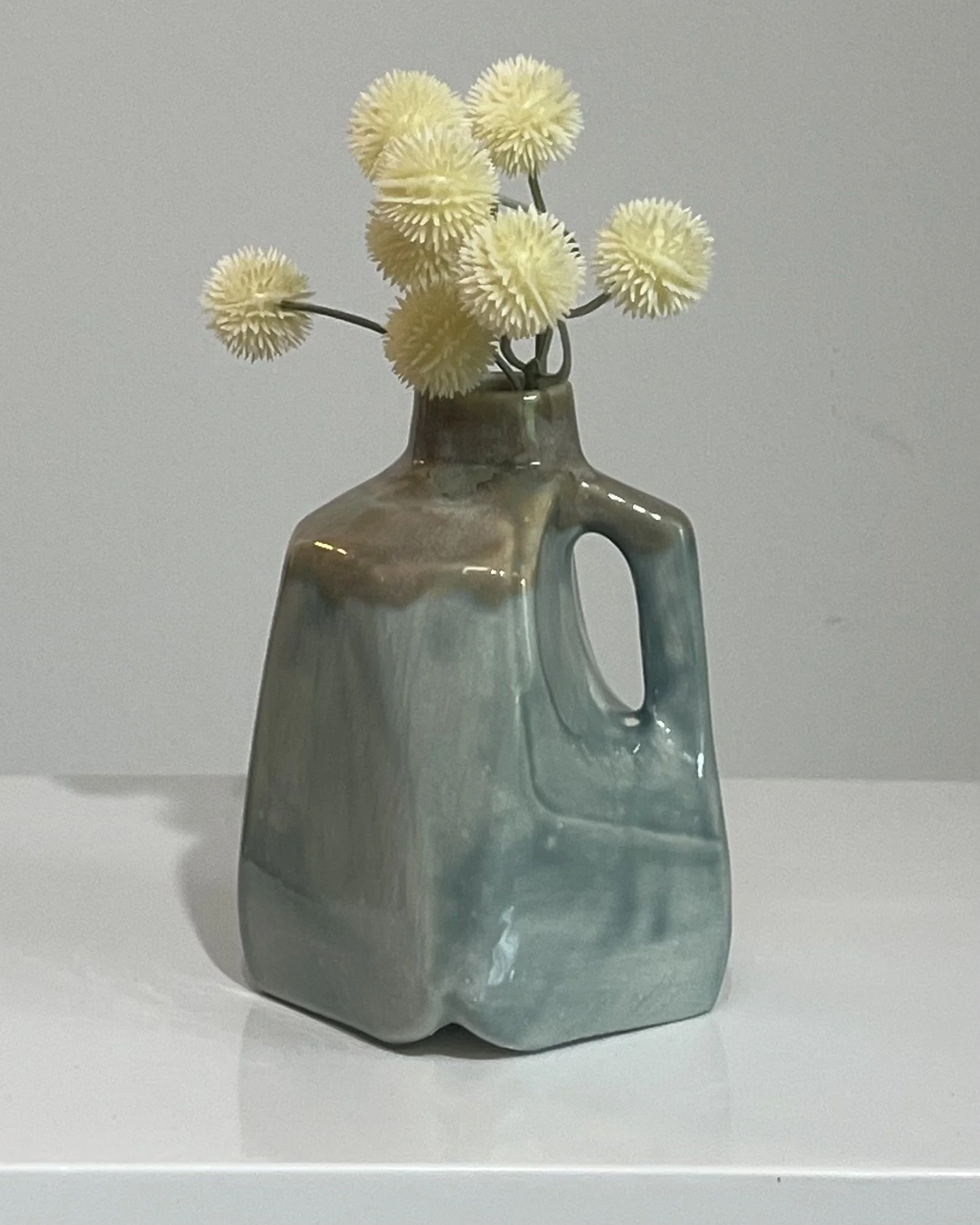Handmade porcelain milk jug with layered White Satin Matte and Mystic Tide glazes displayed with dried flowers.