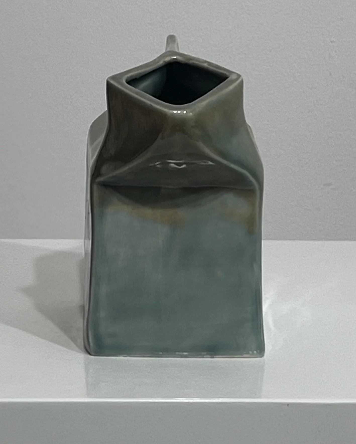 Back view of ceramic milk carton showing folded carton form and dark glazed opening.