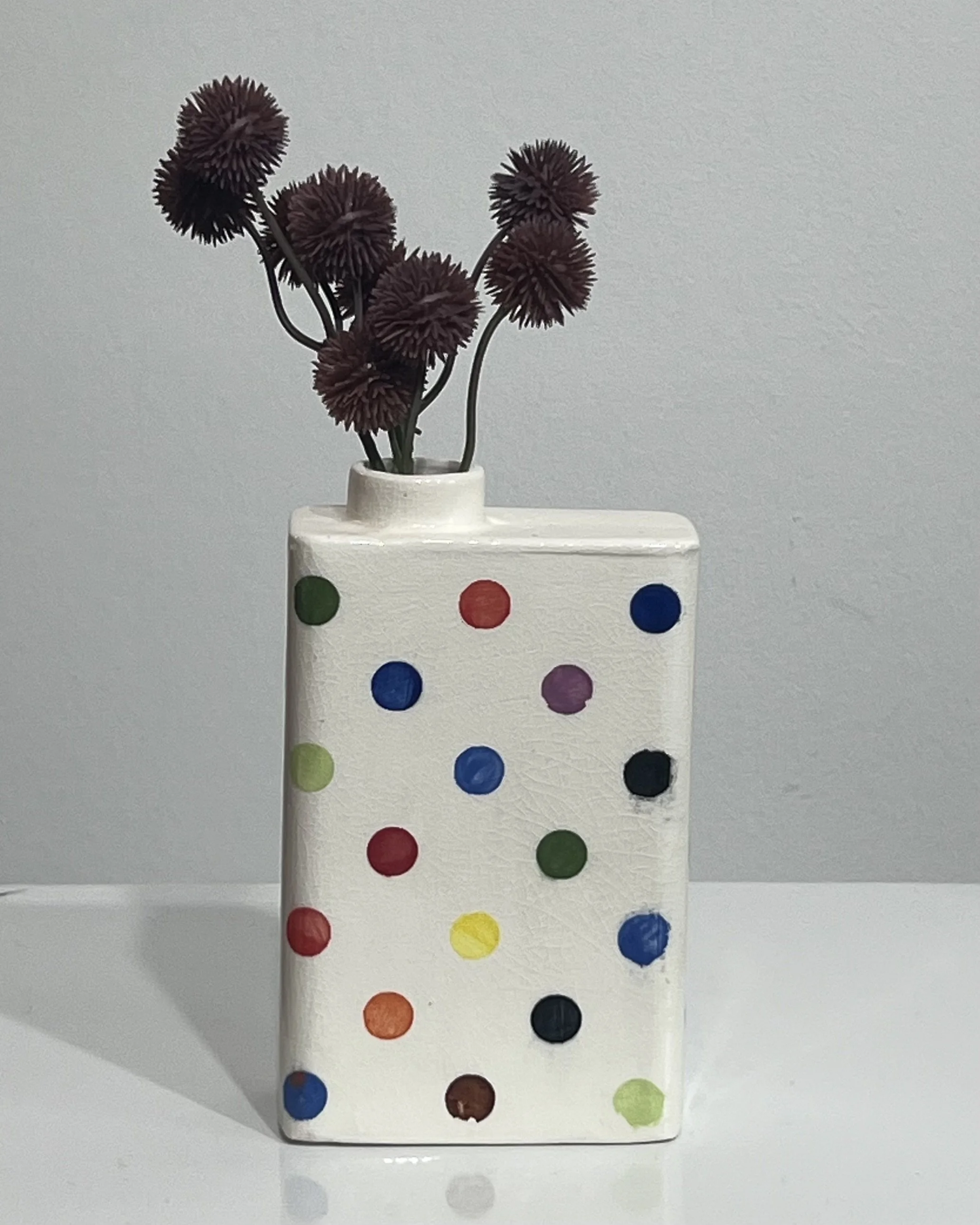 Multicolor polka dot porcelain carton vase by Alissa Van Atta styled with dark flowers