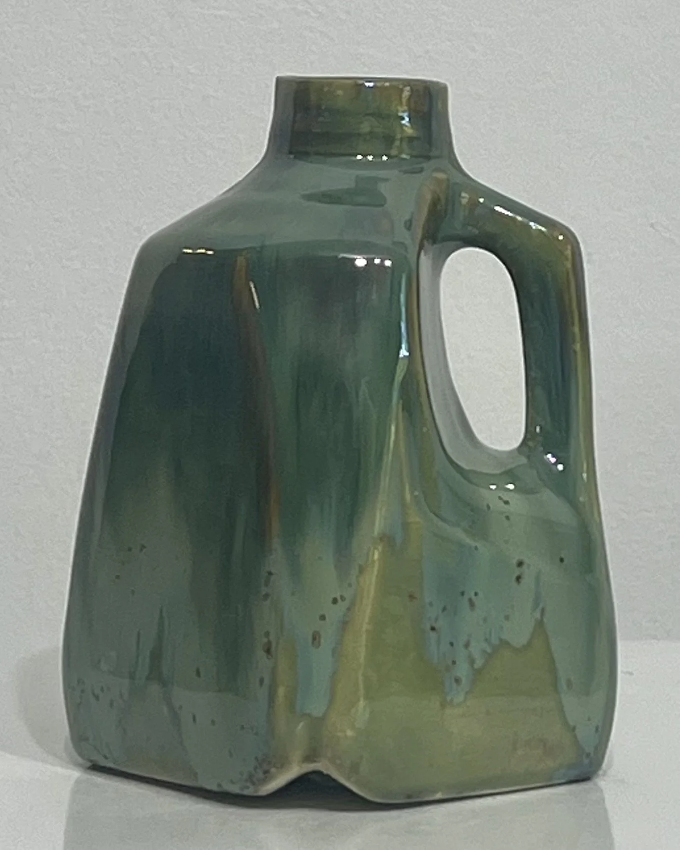 Front view of an olive and jade green handmade porcelain milk jug by Alissa Van Atta.
